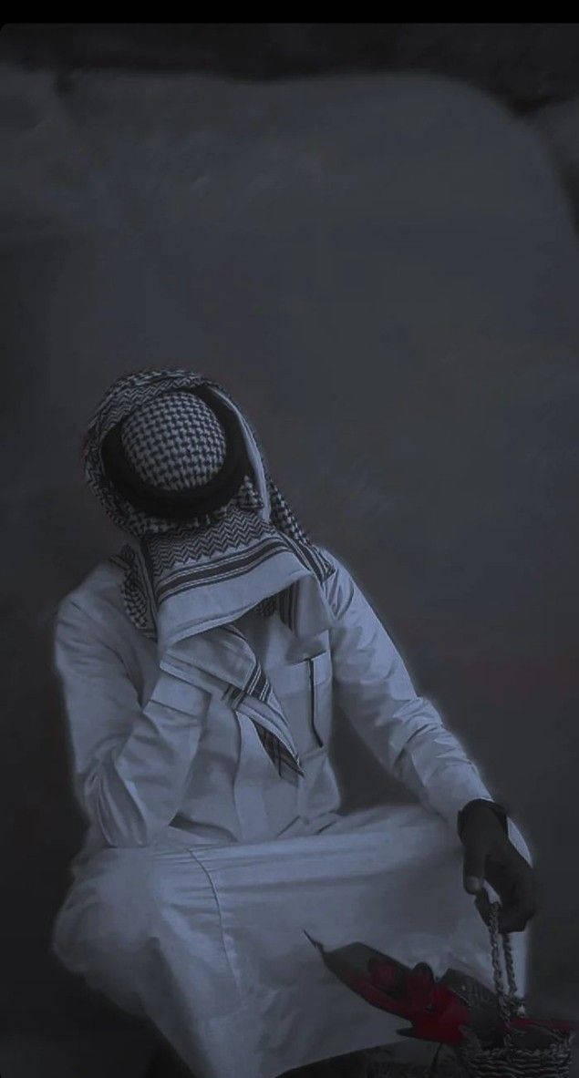 一個穿著傳統服飾的男人在昏暗的環境中手持念珠。