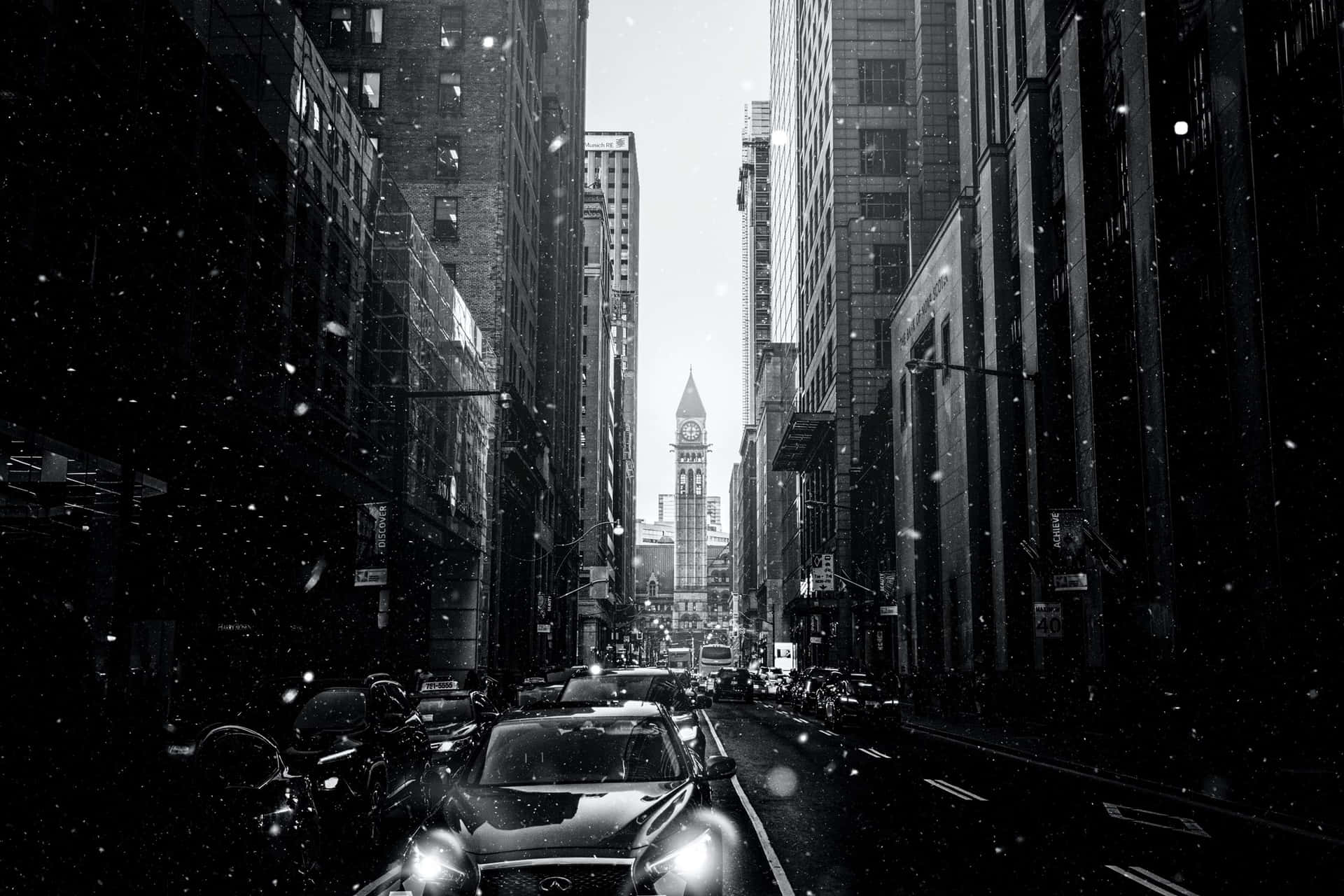 雪落在城市街道上，有汽車和遠處的鐘樓。
