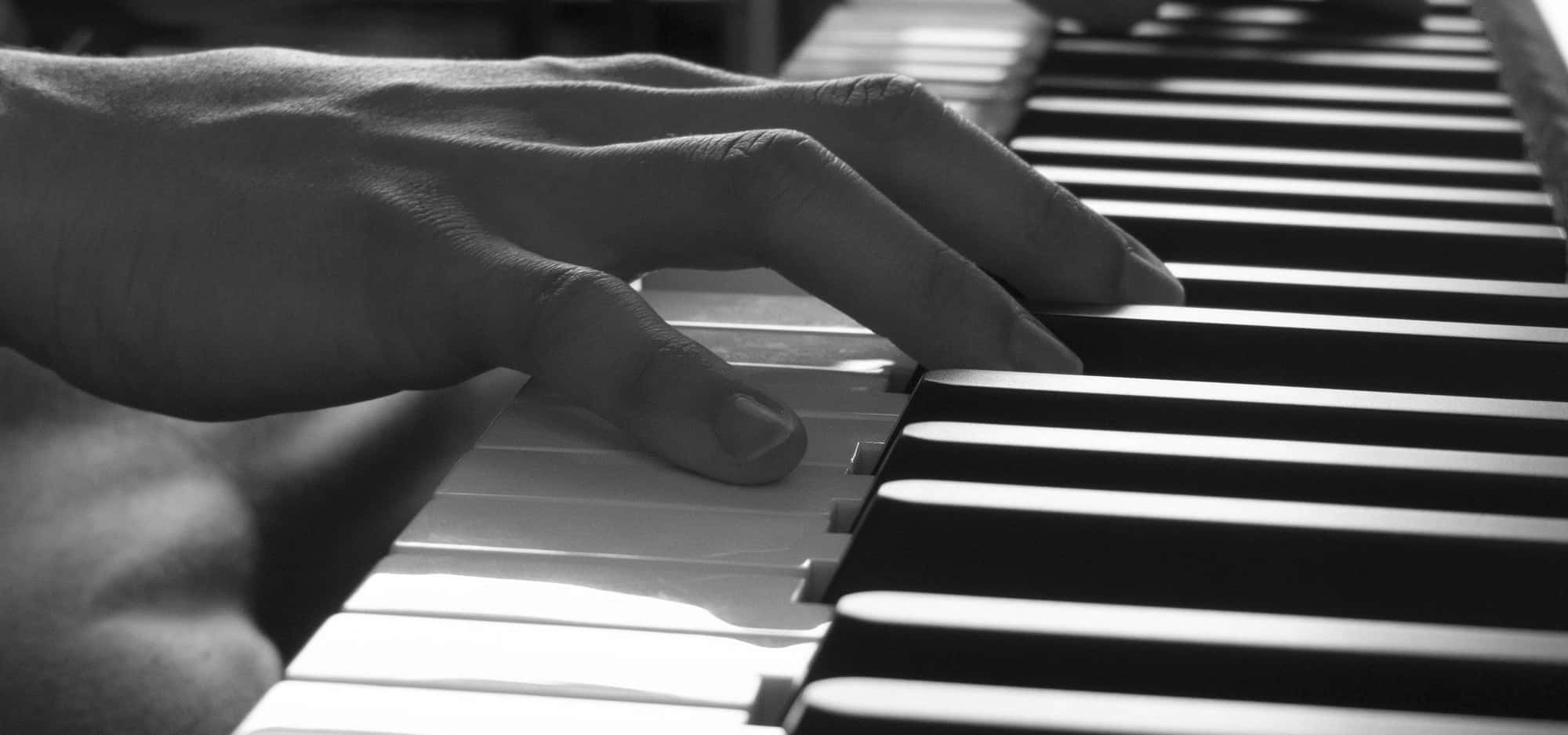 Black And White Piano 桌布 壁紙 — 單色特寫，雙手優雅地按壓鋼琴琴鍵，帶有柔和陰影和高光。