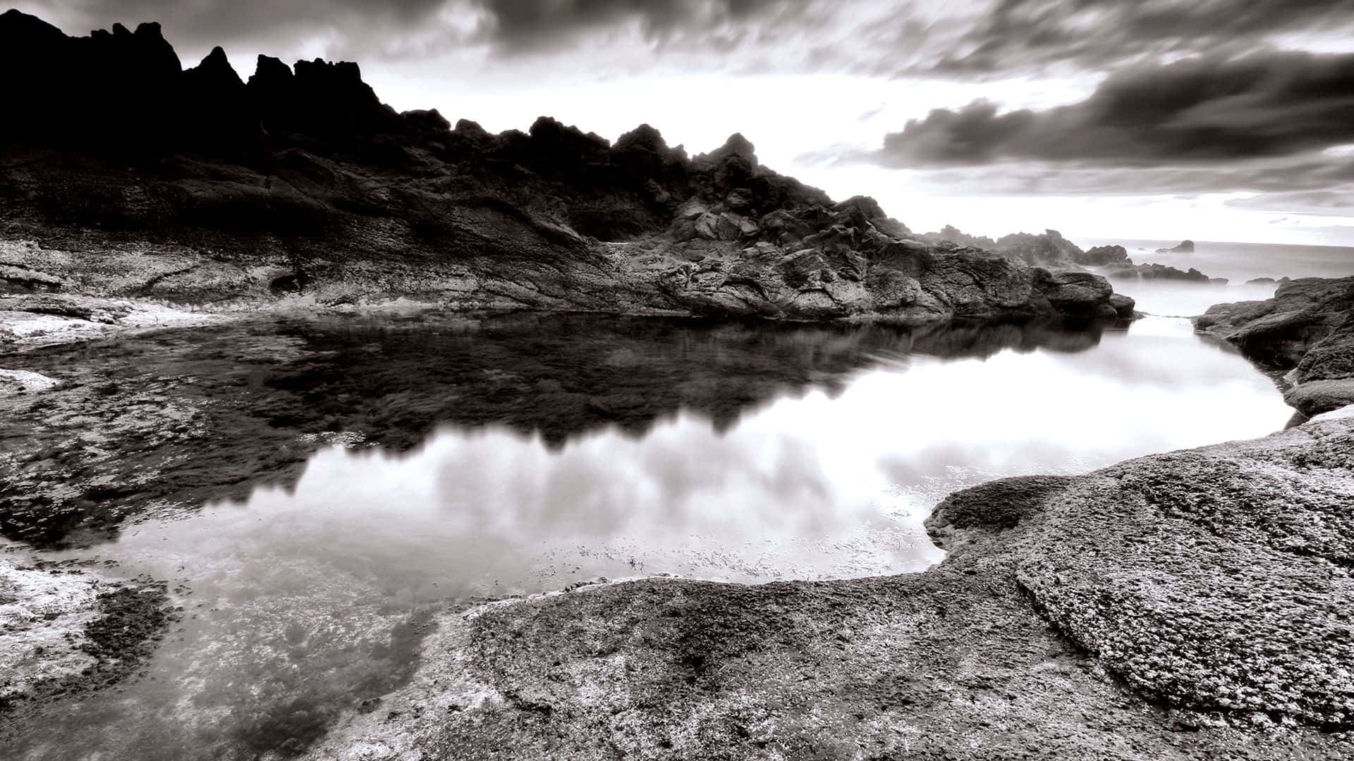 Black And White Landscape 桌布 壁紙 — 單色風景，鋸齒狀懸崖倒映在平靜的潮汐池中，上方是戲劇性的多雲天空。