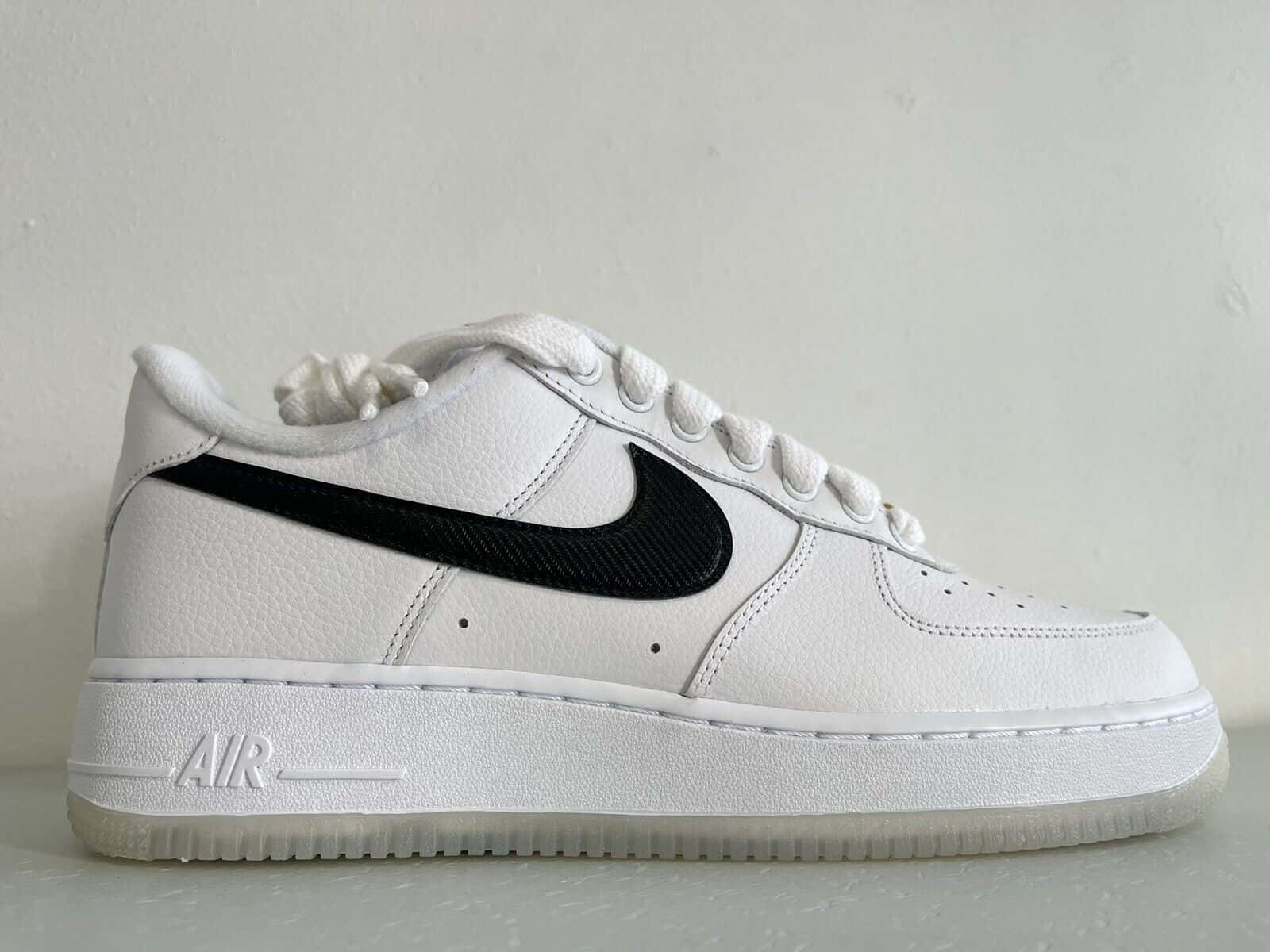 純色背景上帶有黑色Swoosh的白色Nike Air Force 1運動鞋。
