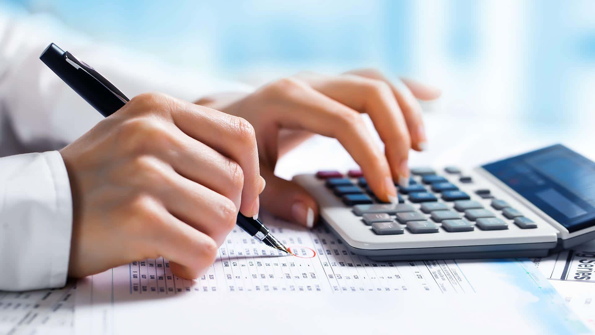 Calculator 桌布 壁紙 — 喺明亮嘅辦公室環境中，用計算機同筆審查財務文件嘅手部特寫。