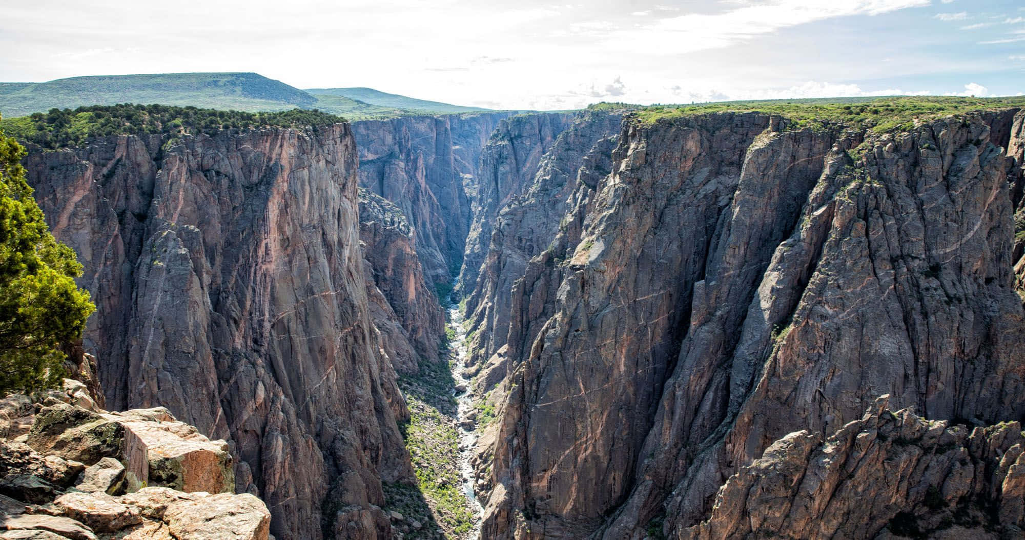 Black Canyon 桌布 壁紙 — 喺明亮天空下，一個深峽谷嘅壯麗景色，有陡峭嘅岩石懸崖同下面蜿蜒嘅河流。