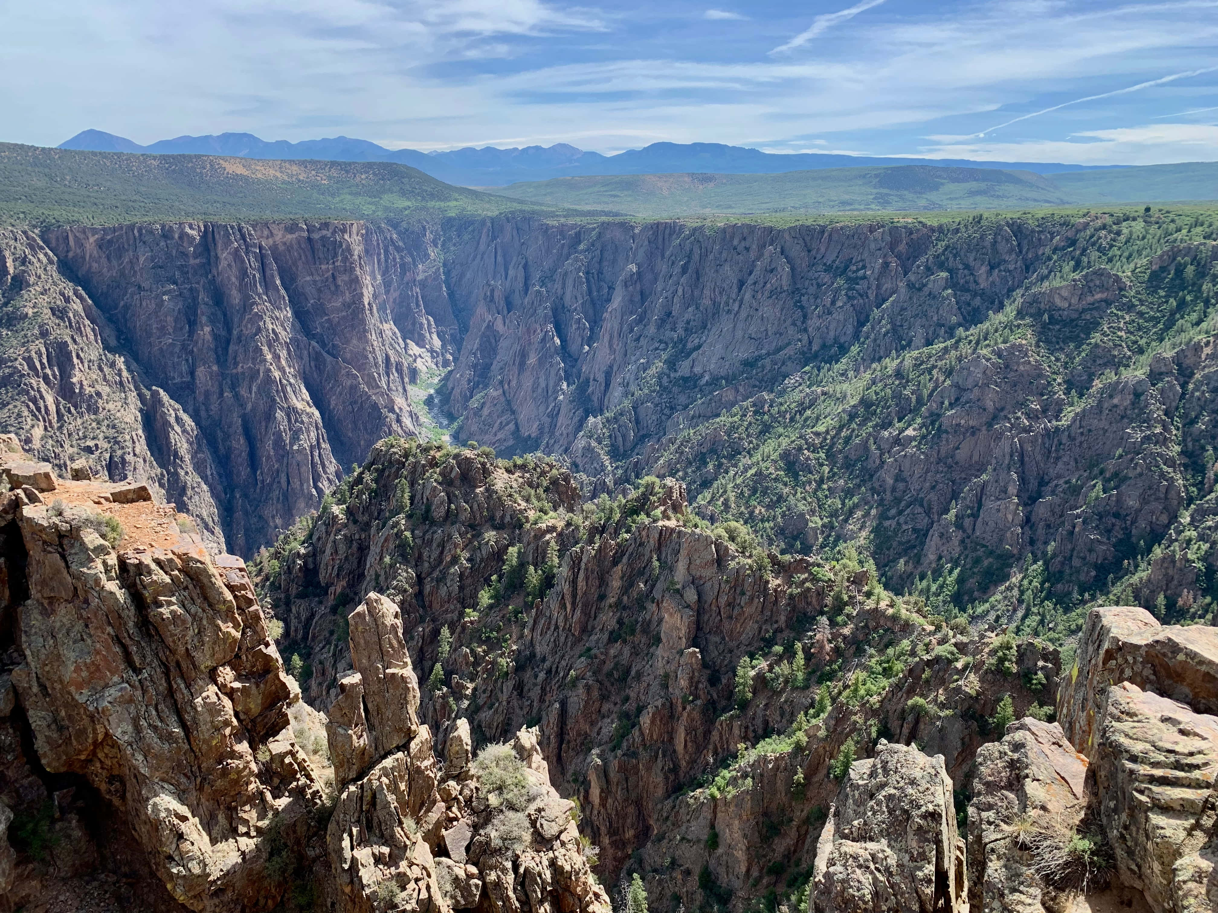 Black Canyon 桌布 壁紙 — 喺明亮藍天下，一個深峽谷嘅壯麗景色，有崎嶇懸崖同綠色植被。