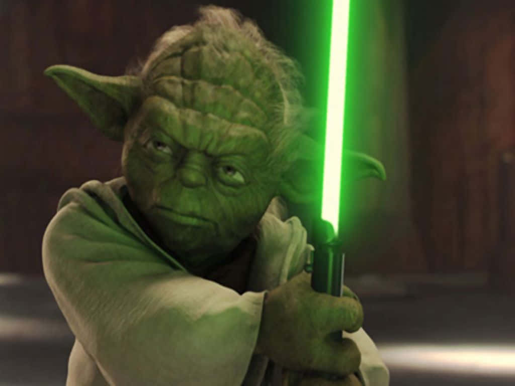 尤達 桌布 壁紙 — 喺昏暗嘅木房間入面，Yoda 拎住一把發光嘅綠色光劍，表情嚴肅。