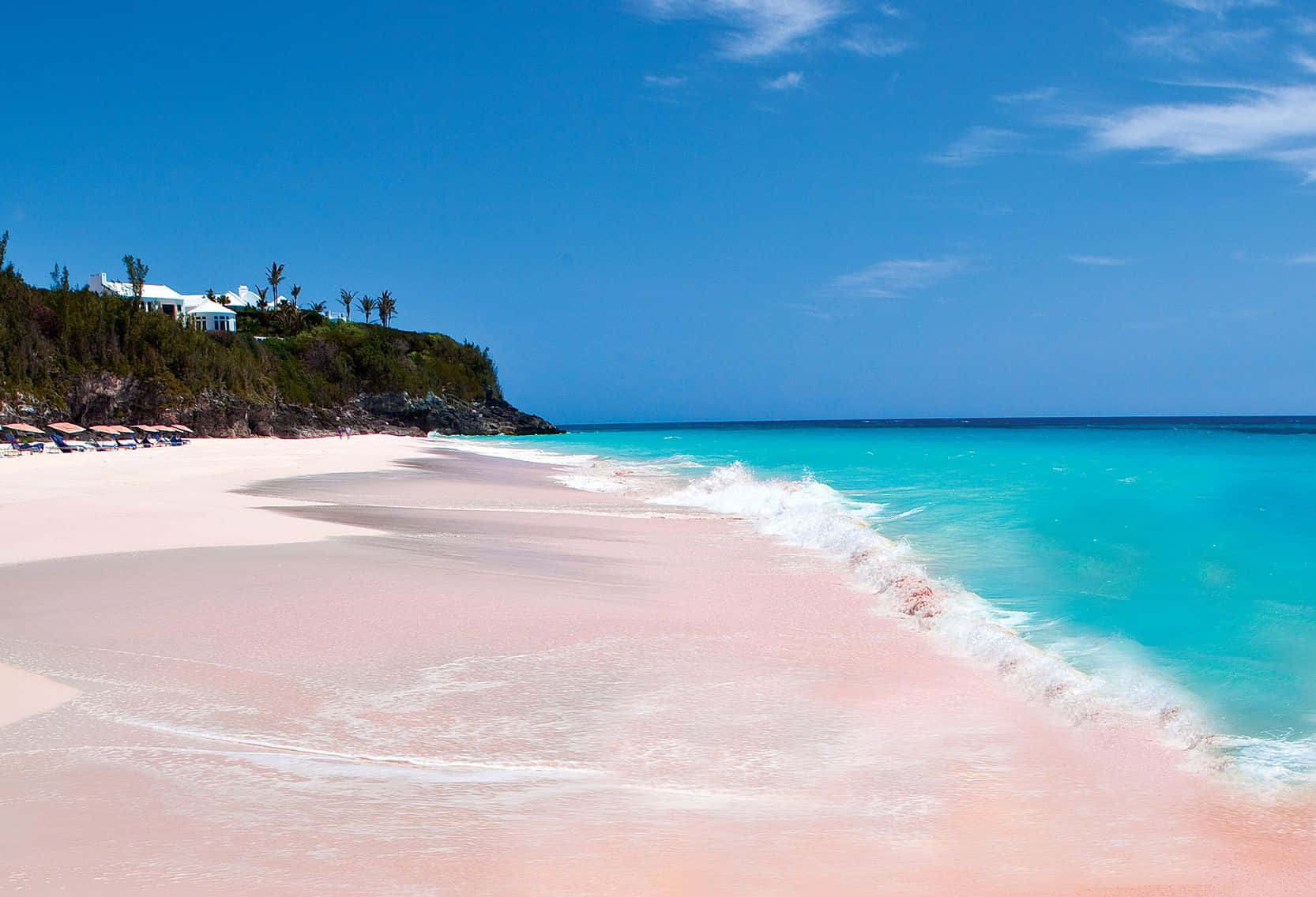 Pink Sand Beach 桌布 壁紙 — 喺晴朗嘅藍天白雲下，一條迷人嘅粉紅色沙灘沿着碧綠嘅海水蜿蜒伸展。