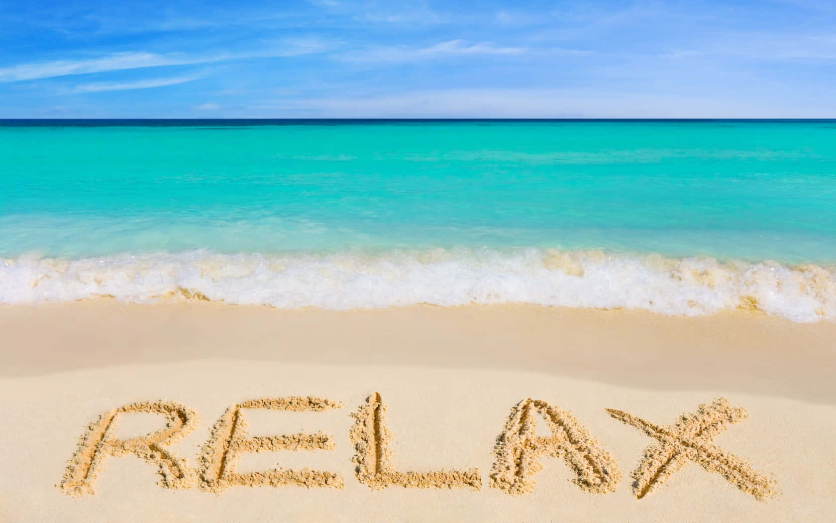 Relaxing Desktop 桌布 壁紙 — 喺清澈藍天之下，純淨沙灘嘅沙上寫住「relax」呢個字，仲有藍綠色海浪湧緊過嚟。