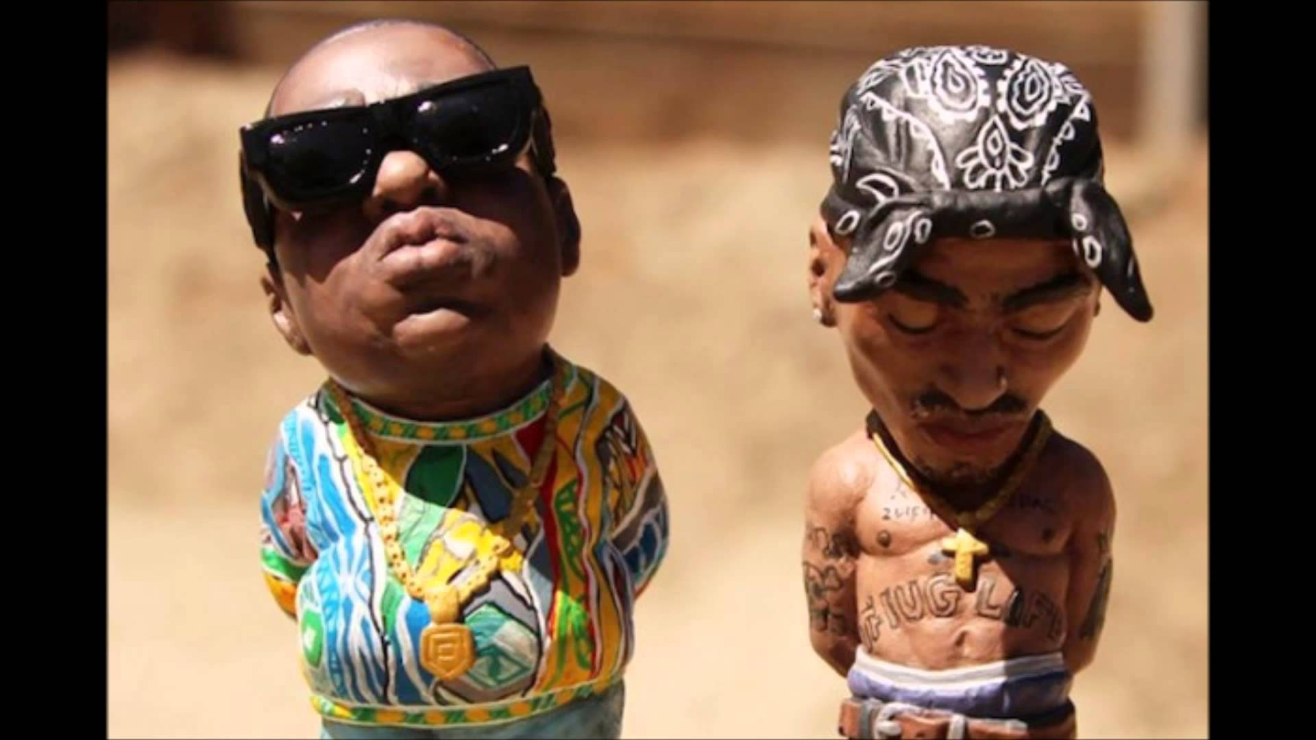 嘻哈傳奇 - 2Pac與The Notorious B.I.G. 壁紙 — 兩個標誌性嘻哈藝術家的風格化人偶並排站在沙質背景前。