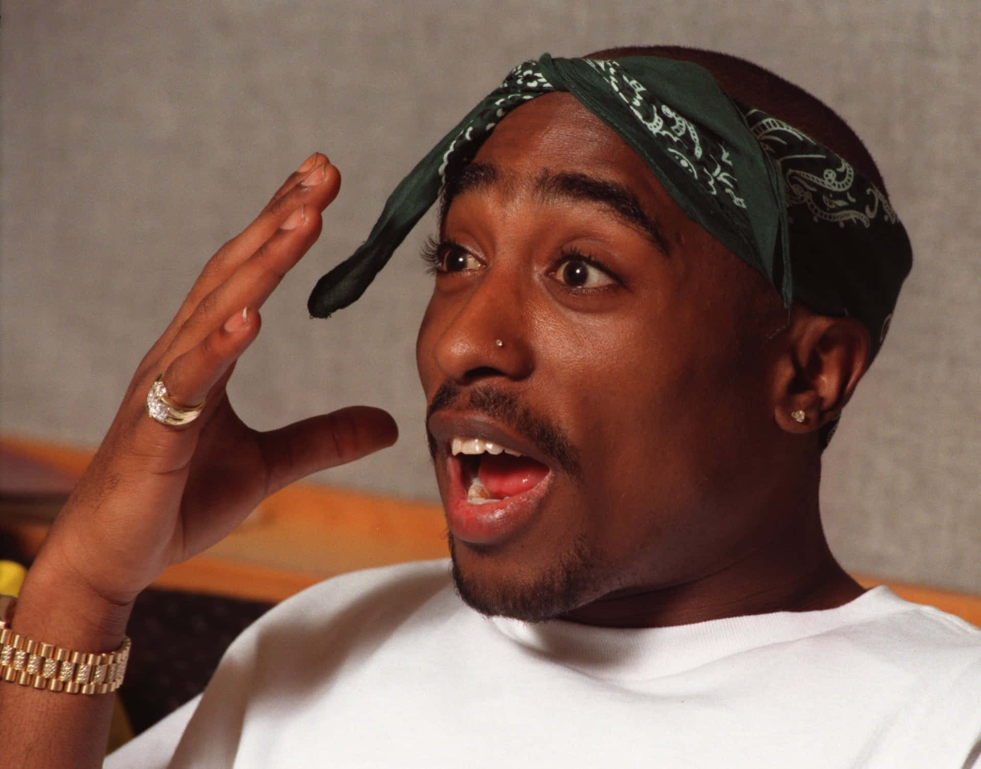 Tupac Shakur 驚訝姿勢，戴著綠色頭巾和金飾。