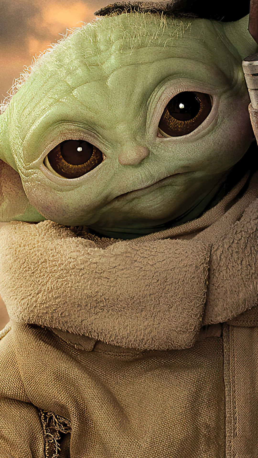 嘿，Baby Yoda！ 壁紙 — Grogu 嘅大而有表現力嘅眼睛同皺紋綠色臉部特寫，包裹喺米色連帽長袍入面。
