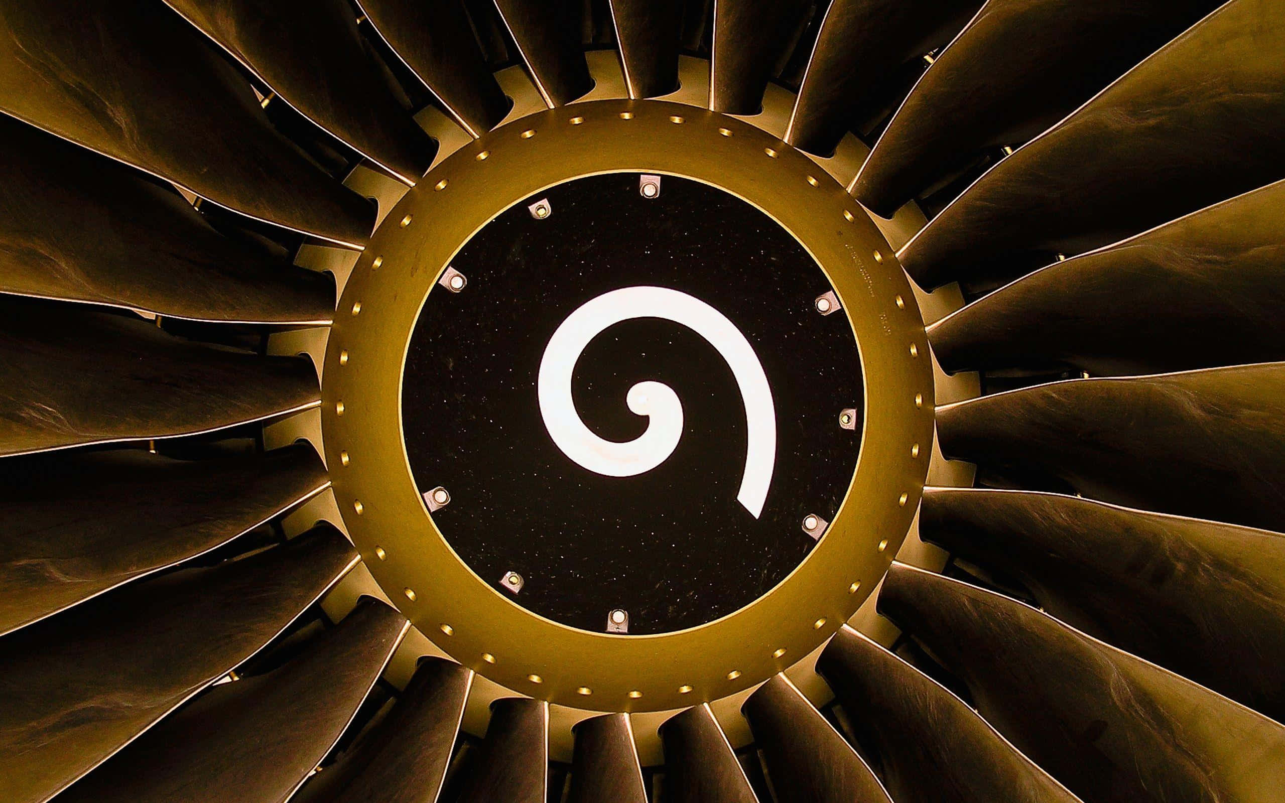 Jet Engine 桌布 壁紙 — 噴射引擎渦輪的近距離視圖，黑色中心有一個發光的白色螺旋標誌，周圍環繞著金色葉片。