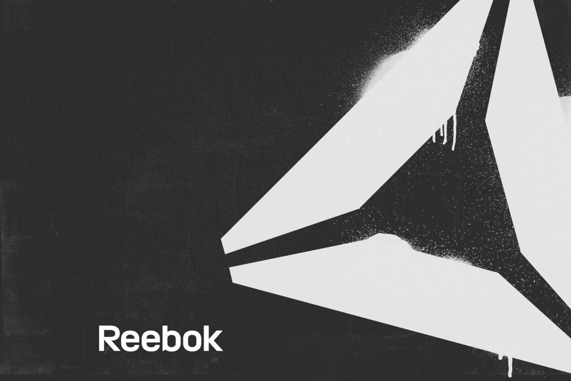 Reebok標誌用白色噴漆畫在黑色紋理牆上，帶有滴落。