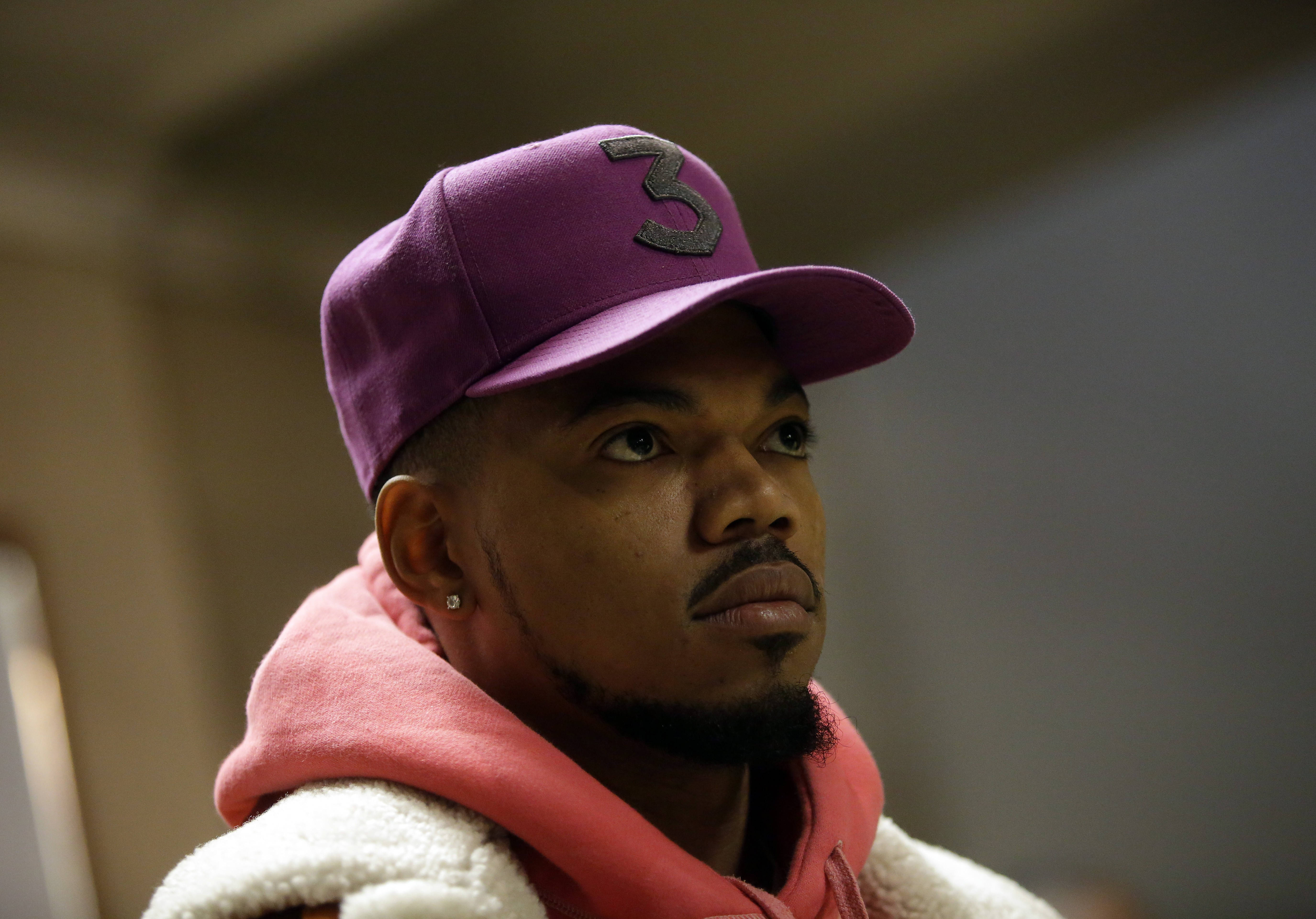 嚴肅的Chance the Rapper 壁紙 — 一個戴著紫色帽子、上有灰色數字三標誌、身穿粉紅色連帽衫的男人若有所思地望向一旁。