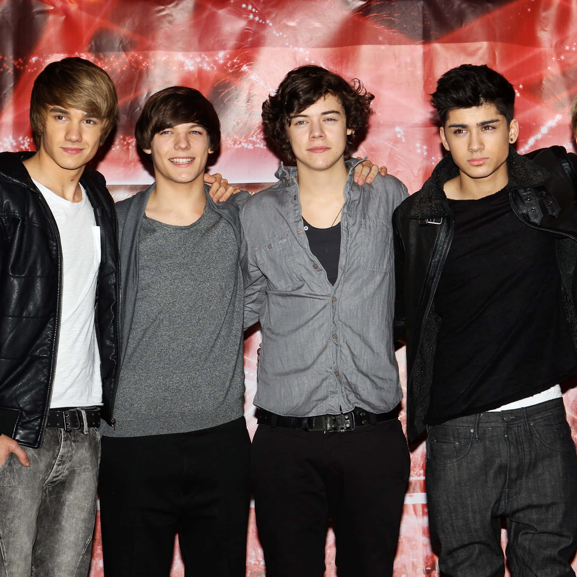 One Direction 桌布 壁紙 — 四位年輕男性樂隊成員在充滿活力的紅色紋理背景前一起擺姿勢，背景帶有發光的閃爍效果。