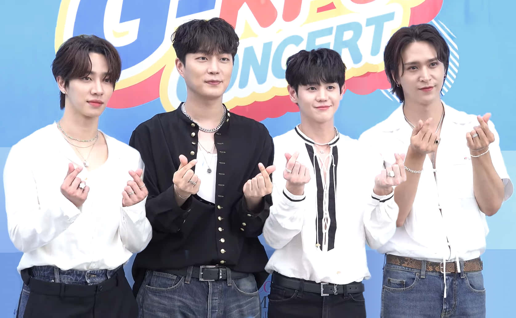 四位男性K-pop偶像在音樂會活動中用手勢擺姿勢。