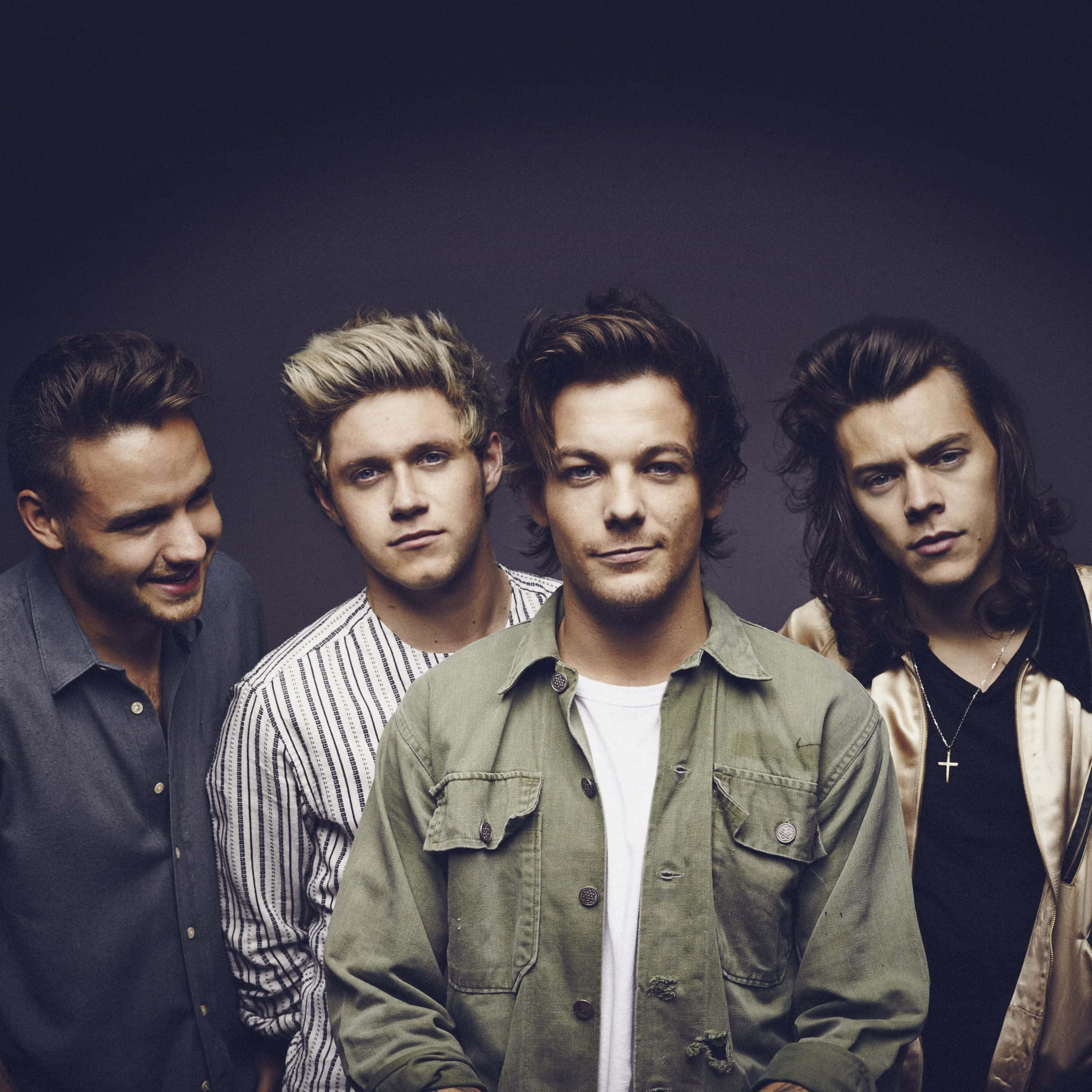 One Direction 桌布 壁紙 — 四位時尚年輕男性在昏暗的攝影棚背景前自信地擺姿勢，燈光效果戲劇化。