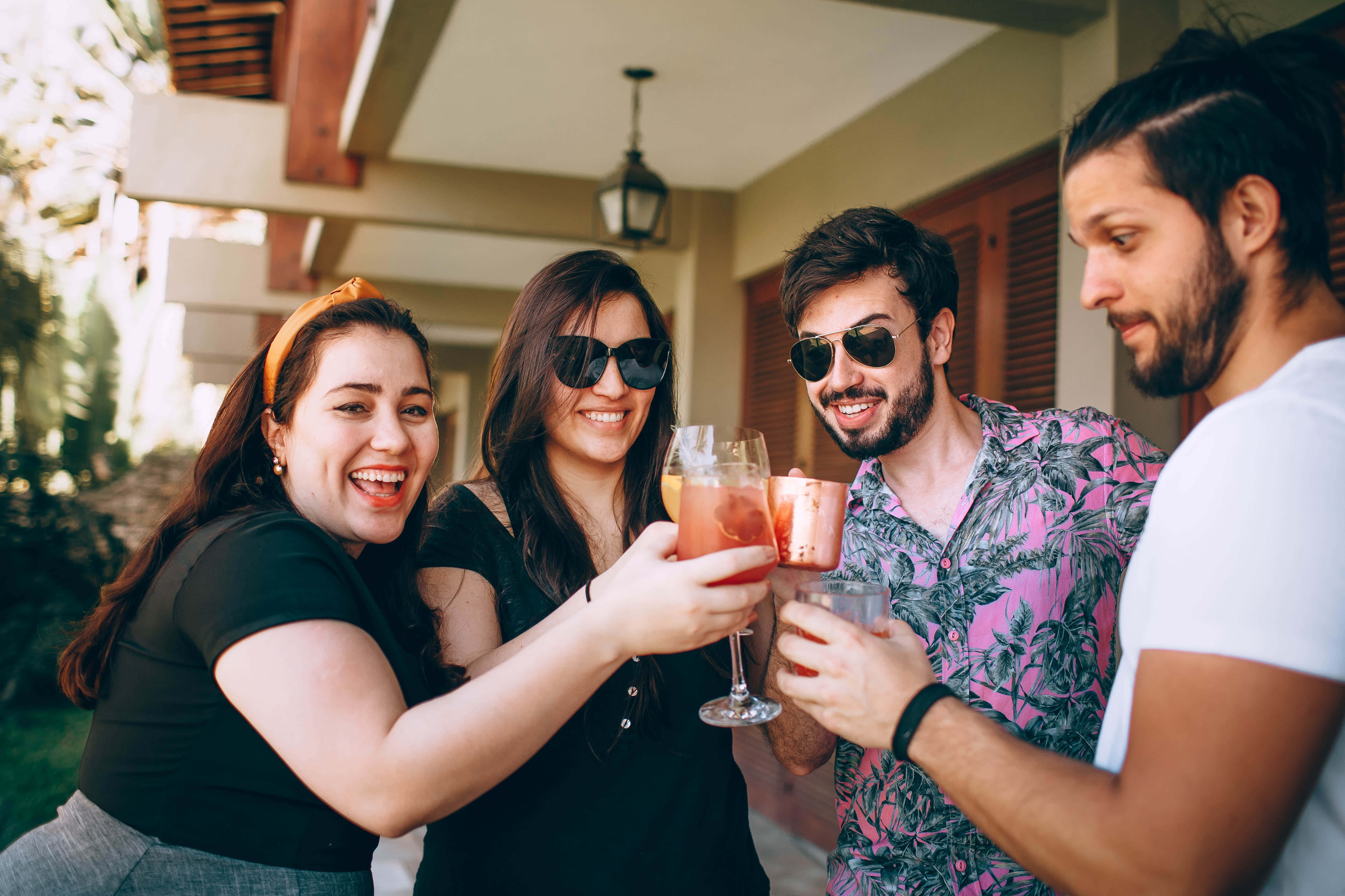 Summer Drinks 桌布 壁紙 — 四位朋友在有蓋露台上，在溫暖的陽光下用色彩繽紛的雞尾酒乾杯。