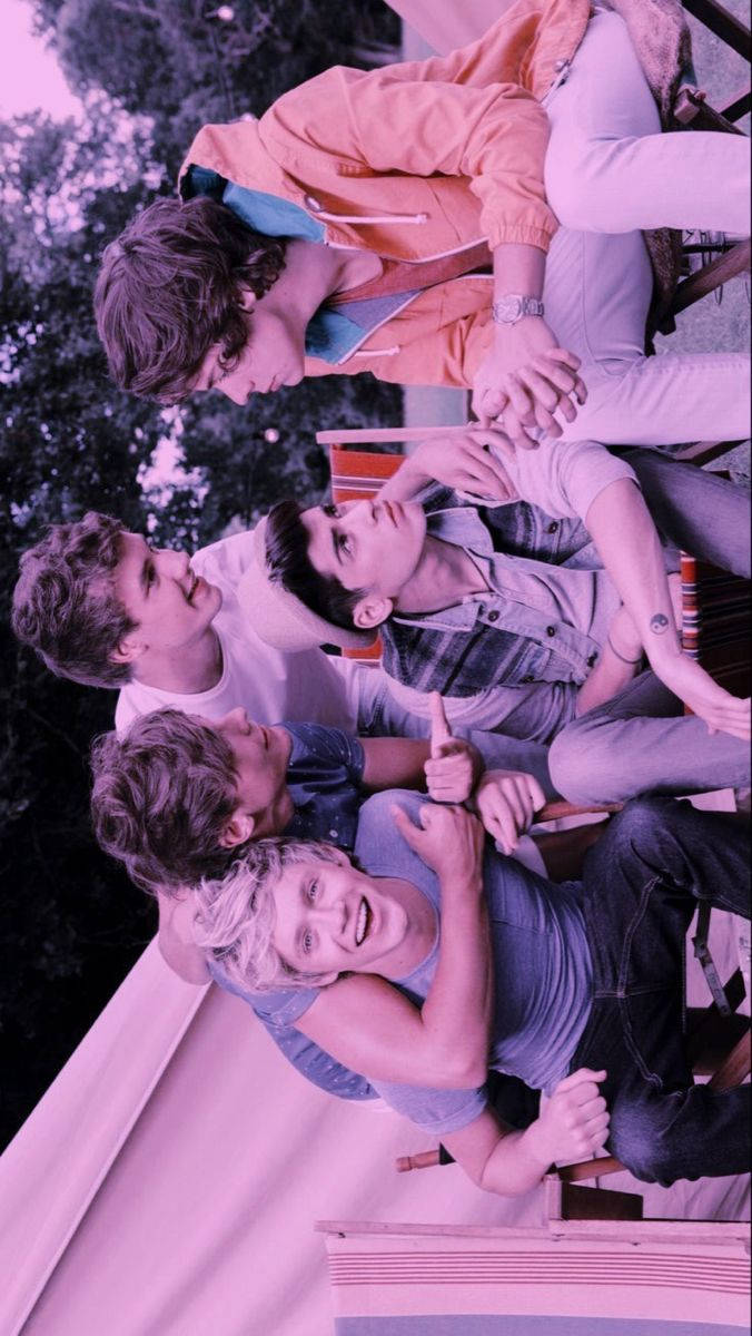 One Direction Aesthetic 桌布 壁紙 — 四位穿著休閒服的年輕男子在帶有紫色調的天空下以俏皮的群體姿勢靠在一起。