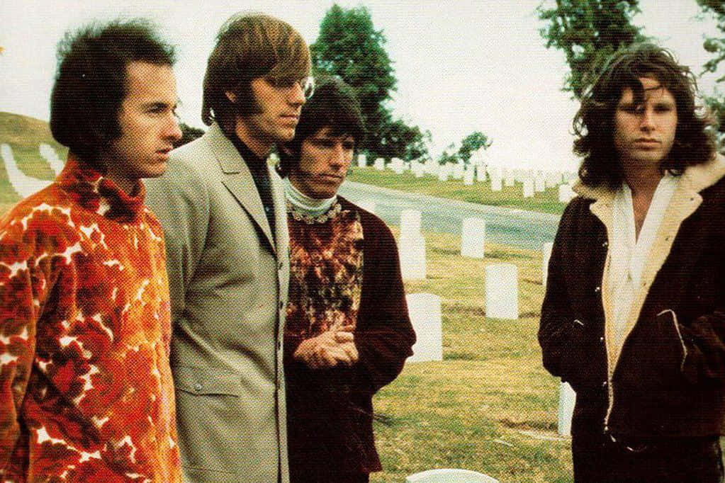  壁紙 — 四位身穿1970年代時尚的男子，在陰天下的白色墓碑墓地中莊嚴地站立。