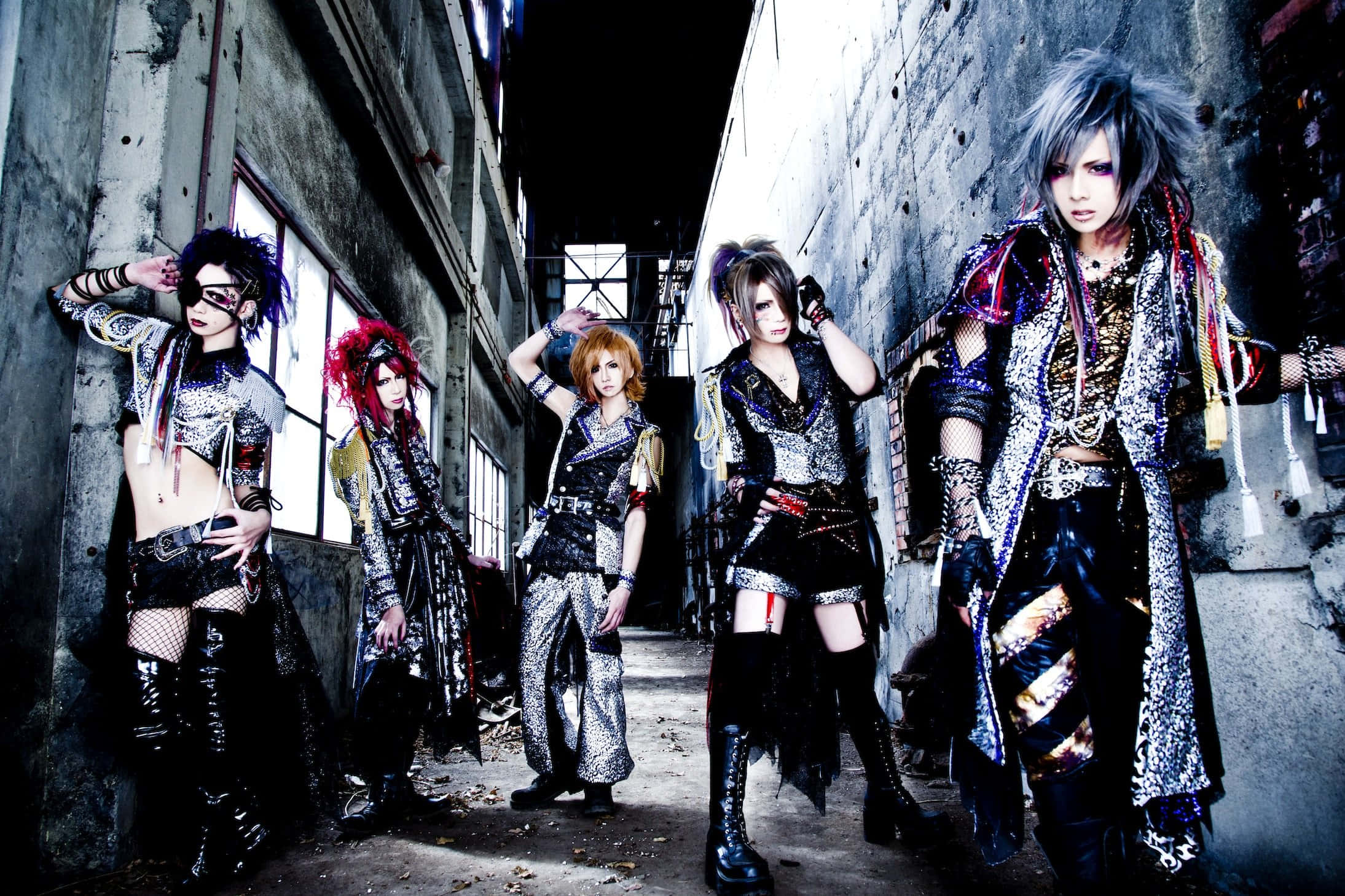 J-rock 桌布 壁紙 — 四位風格化的表演者穿著精緻的哥德式時裝，在骯髒的城市小巷中戲劇性地擺姿勢。