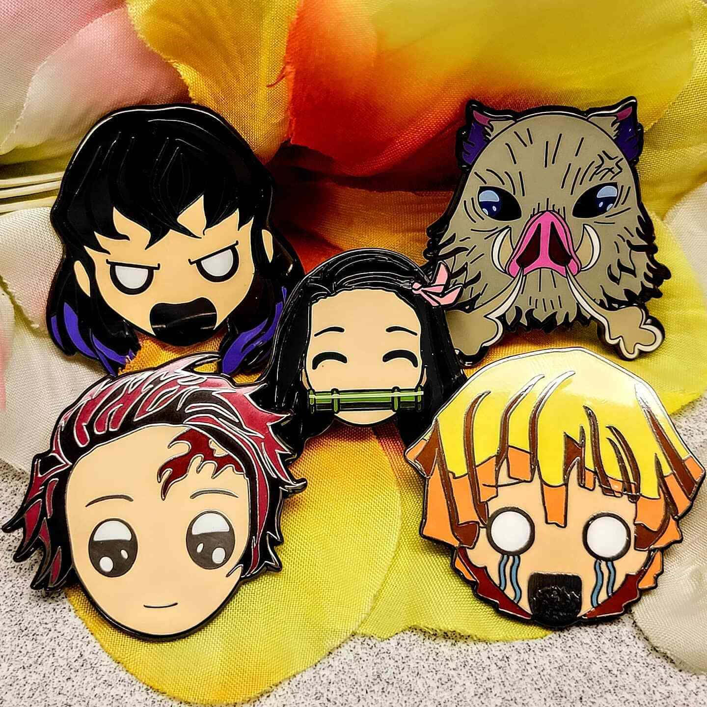 Demon Slayer Corps 桌布 壁紙 — 四個Q版風格動漫角色徽章，包括一個紫髮女孩、一個野豬面具、一個紅髮男孩和一個哭泣的金髮男孩，放在色彩繽紛的布料背景上。