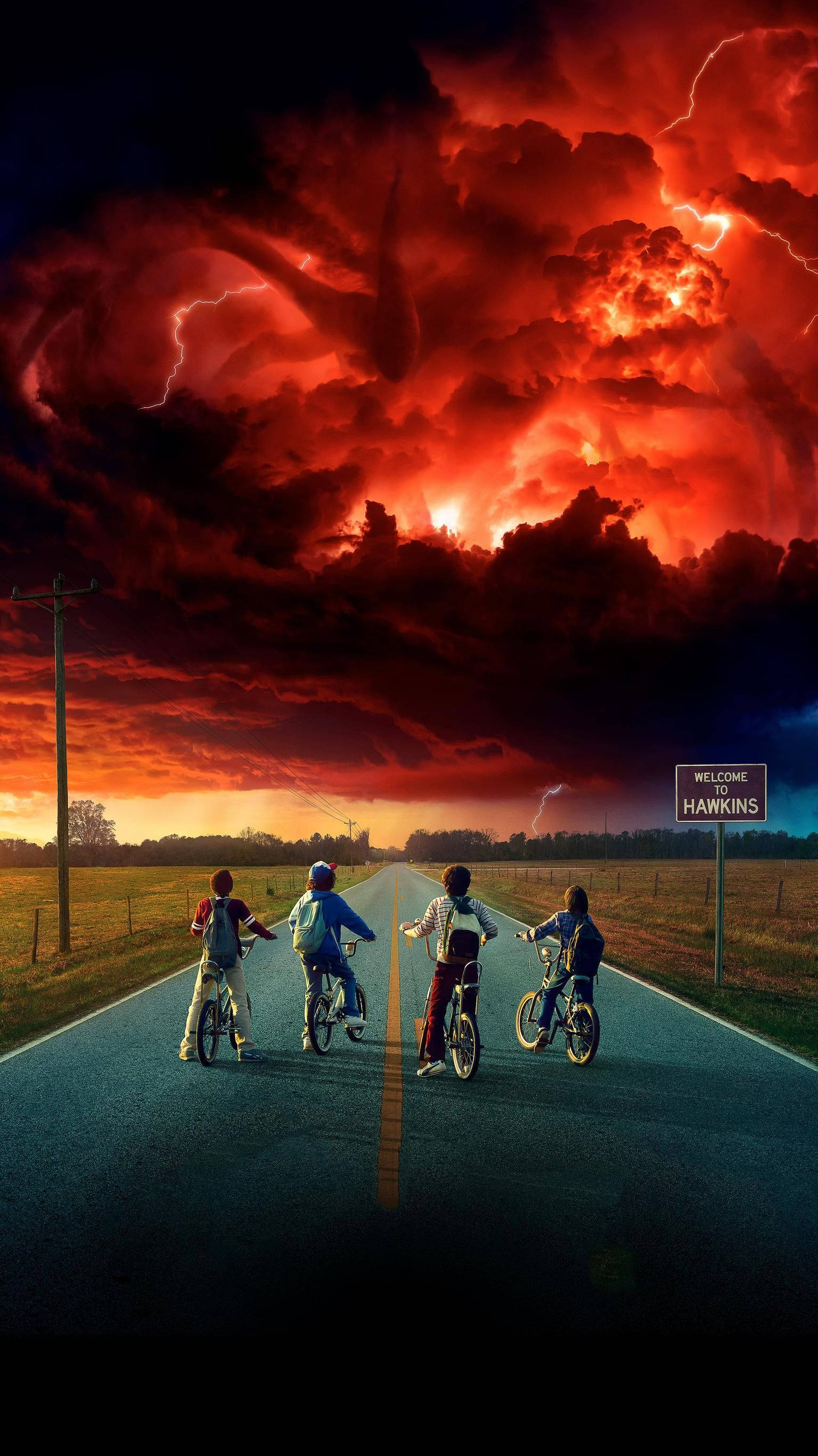 Netflix 桌布 壁紙 — 四個孩子騎著單車沿鄉村道路行駛，朝向戲劇性的紅色天空，伴隨著閃電和一個巨大的怪物輪廓籠罩在上方。