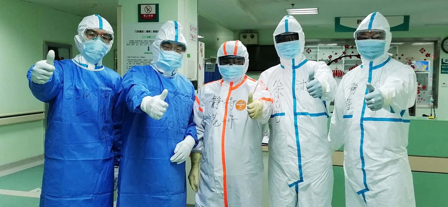 四個穿防護衣的人站在醫院內 壁紙