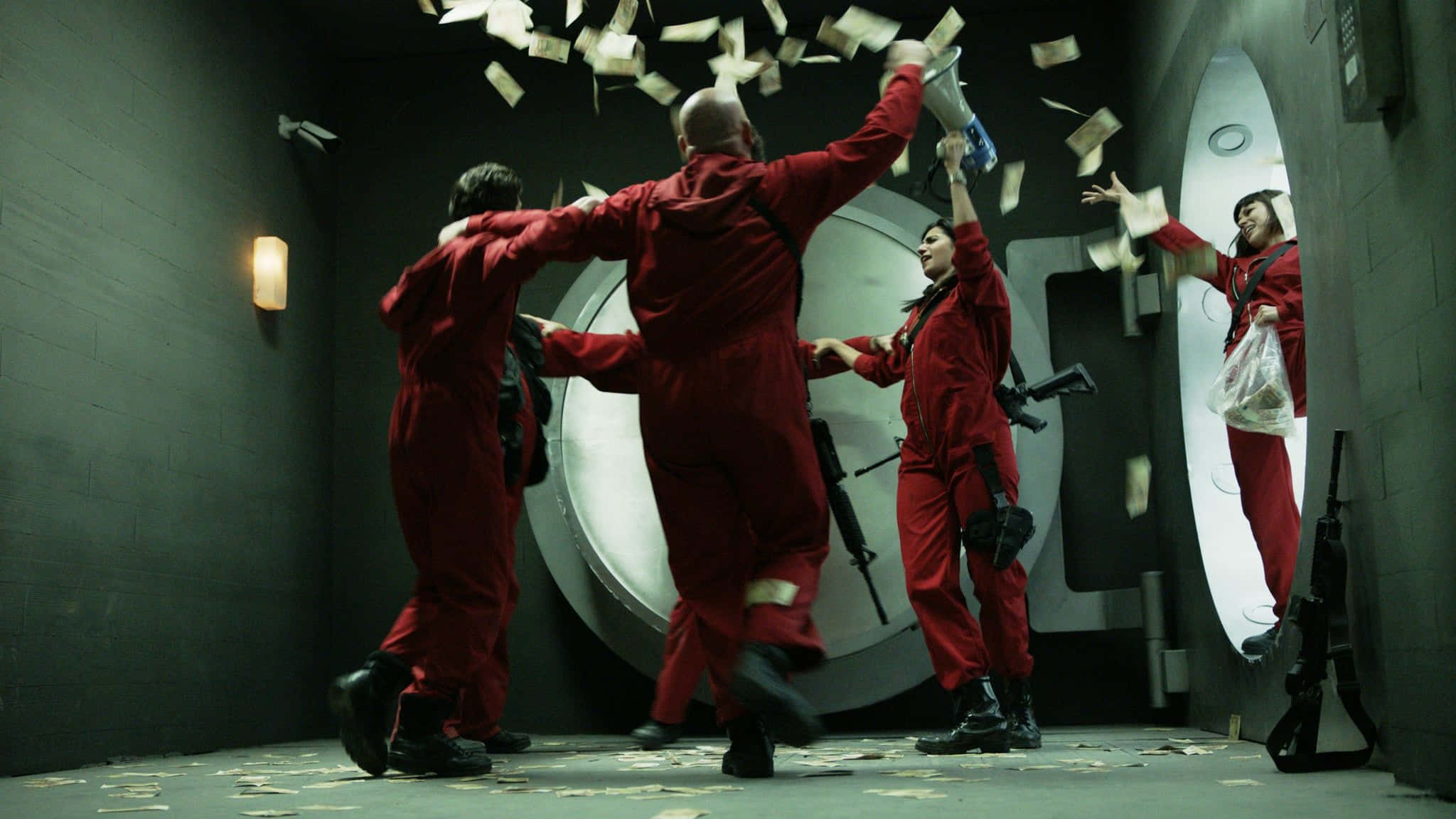 Money Heist 桌布 壁紙 — 四個身穿紅色連身衣的人物在金庫內瘋狂慶祝，金錢如雨般灑落在他們周圍。