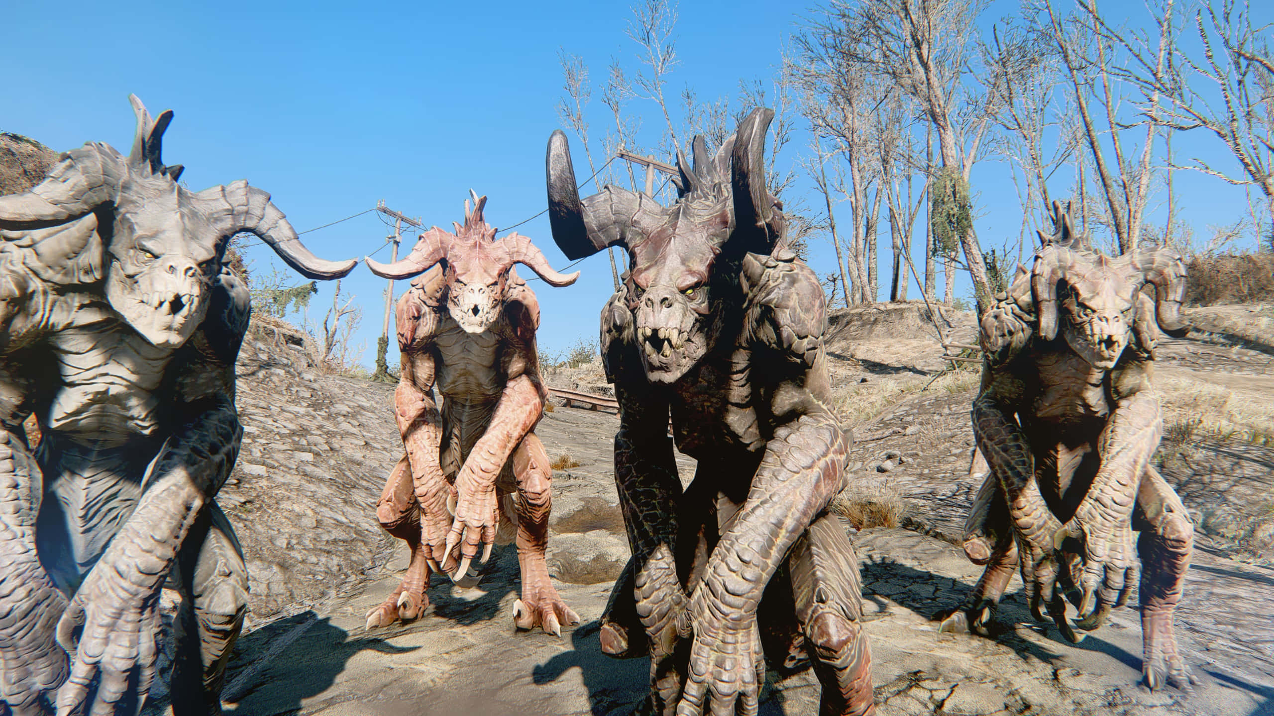 Deathclaw 桌布 壁紙 — 四個長有角、皮膚粗糙的怪獸，在晴朗藍天下的一片貧瘠荒地中威脅性地蹲伏着。