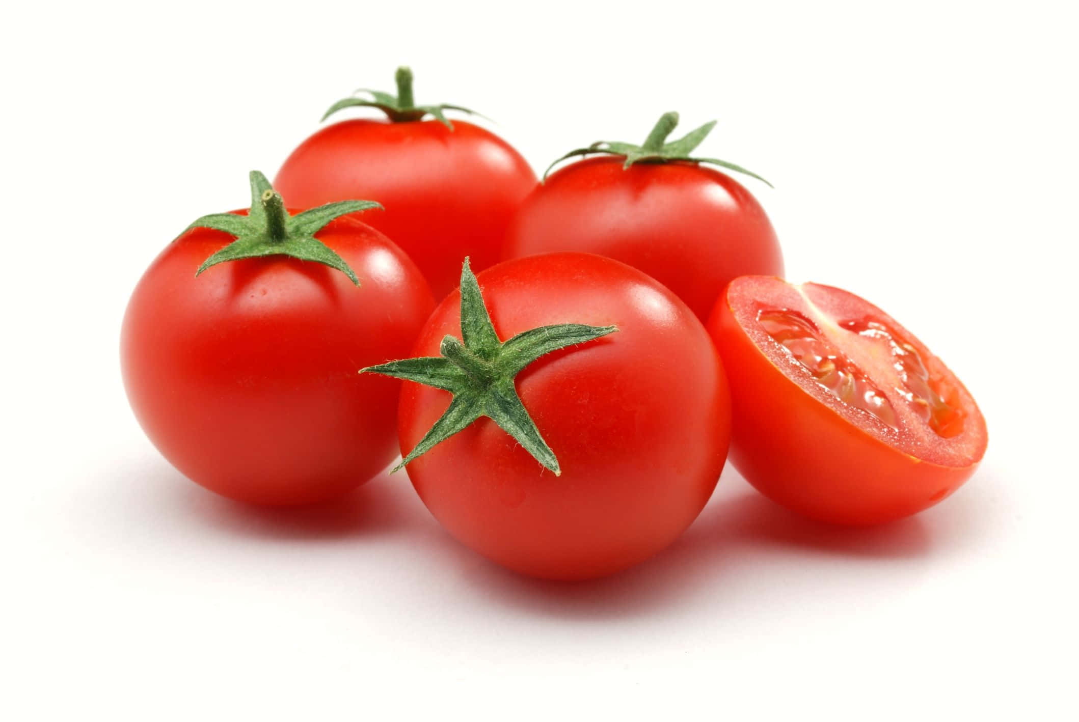 tomato 桌布 壁紙 — 四個鮮紅番茄，帶綠色莖，其中一個切半，放在潔白背景上。