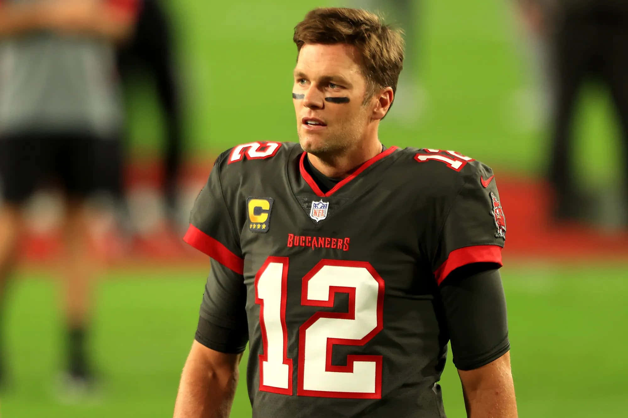 湯姆·布雷迪 桌布 壁紙 — 四分衛湯姆·布雷迪身穿坦帕灣海盜隊12號球衣，在球場燈光下專注地站在場上。