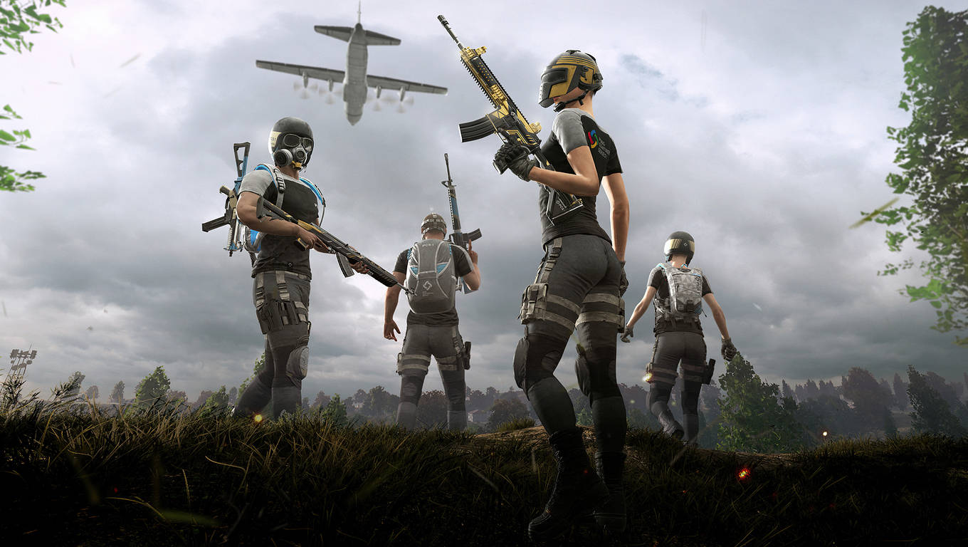 PUBG 桌布 壁紙 — 四名身穿戰術裝備的武裝士兵站在草嶺上，看著一架軍用飛機在多雲的天空下從頭頂飛過。
