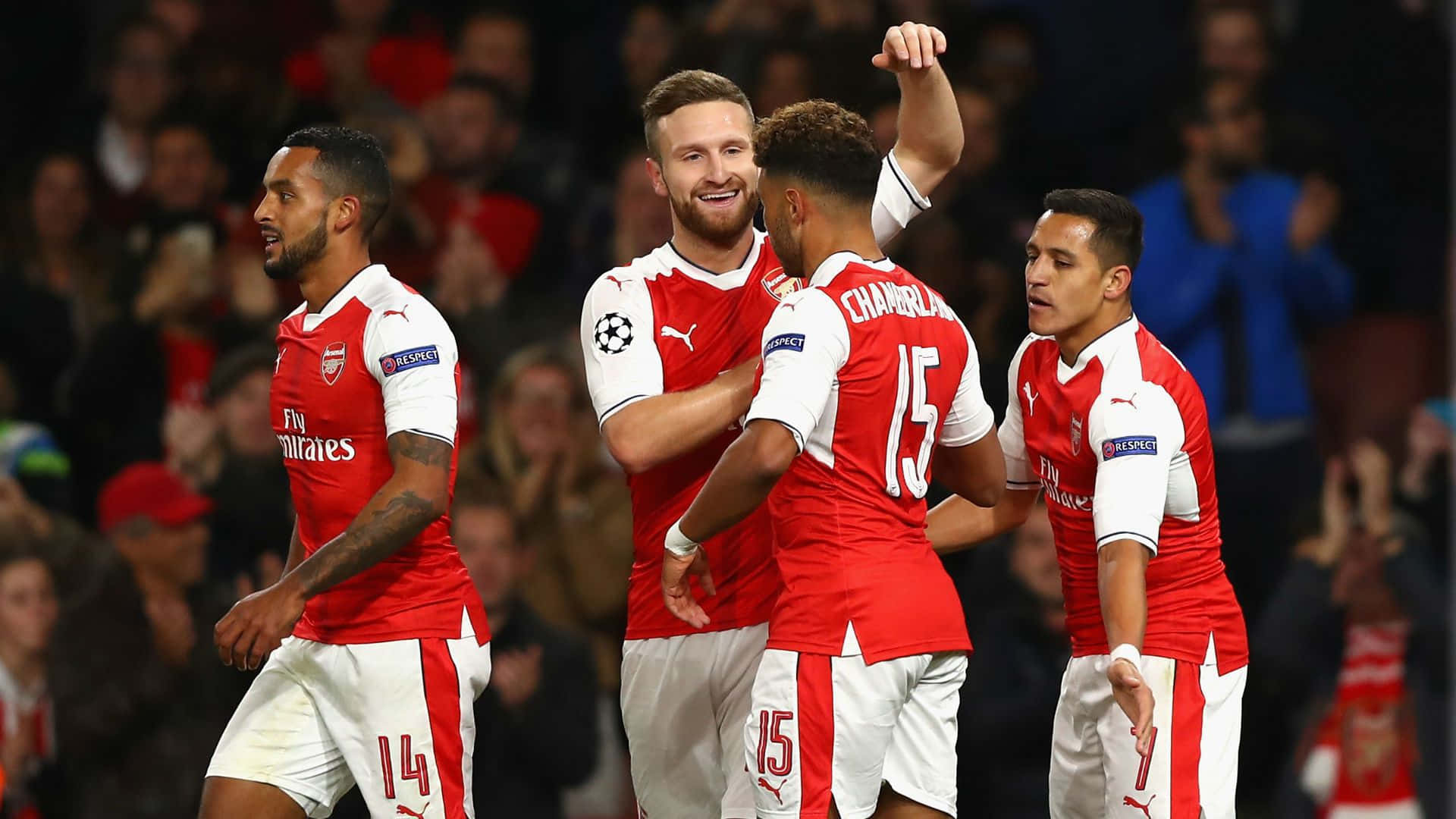 Arsenal 桌布 壁紙 — 四名身穿紅白球衣的阿仙奴足球員在晚上於擠滿觀眾的球場上高舉雙臂，以喜悅的表情慶祝入球。
