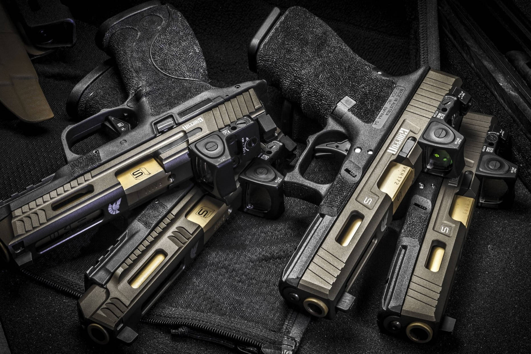 四把戰術 Glock 手槍 壁紙 — 四把戰術手槍配金色滑套，在戲劇性的低光下放置於黑色紋理表面上。