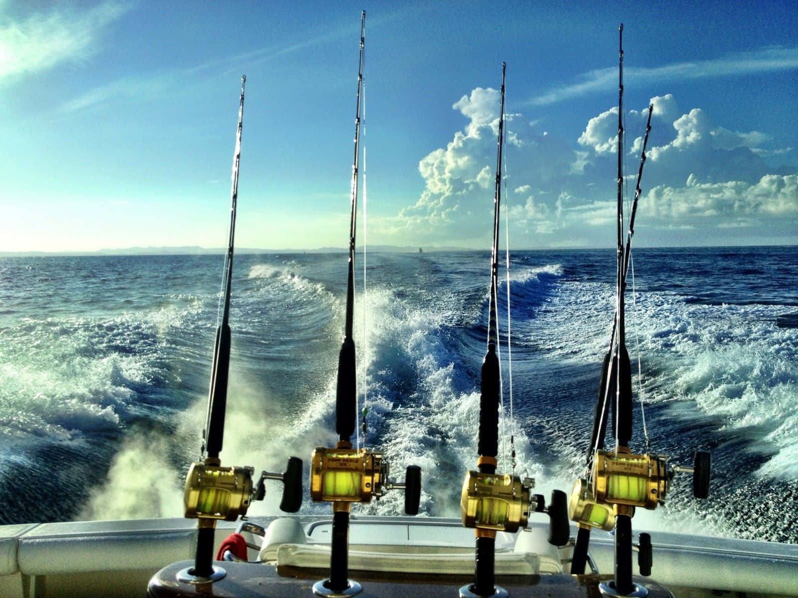 Fishing Rod 桌布 壁紙 — 四支帶金色捲線器的釣竿準備就緒，放在一艘在明亮天空下劃破藍色海浪的快艇上。