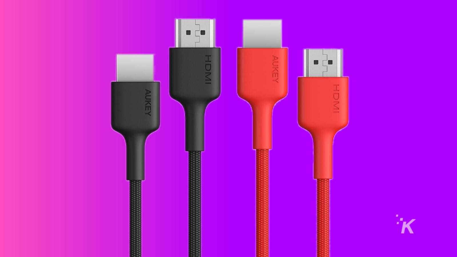 Hdmi 桌布 壁紙 — 四條色彩繽紛的Aukey HDMI線，帶有黑色和紅色編織外皮，立在充滿活力的粉紅到紫色漸變背景前。
