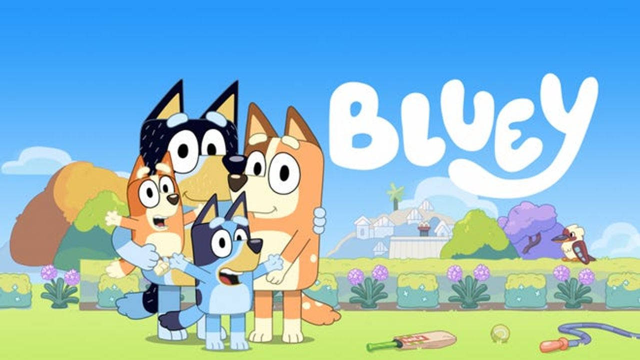 Bluey 桌布 壁紙 — 四隻卡通狗在明亮的後院裡，有玩具和「Bluey」標誌，在晴朗的藍天下。