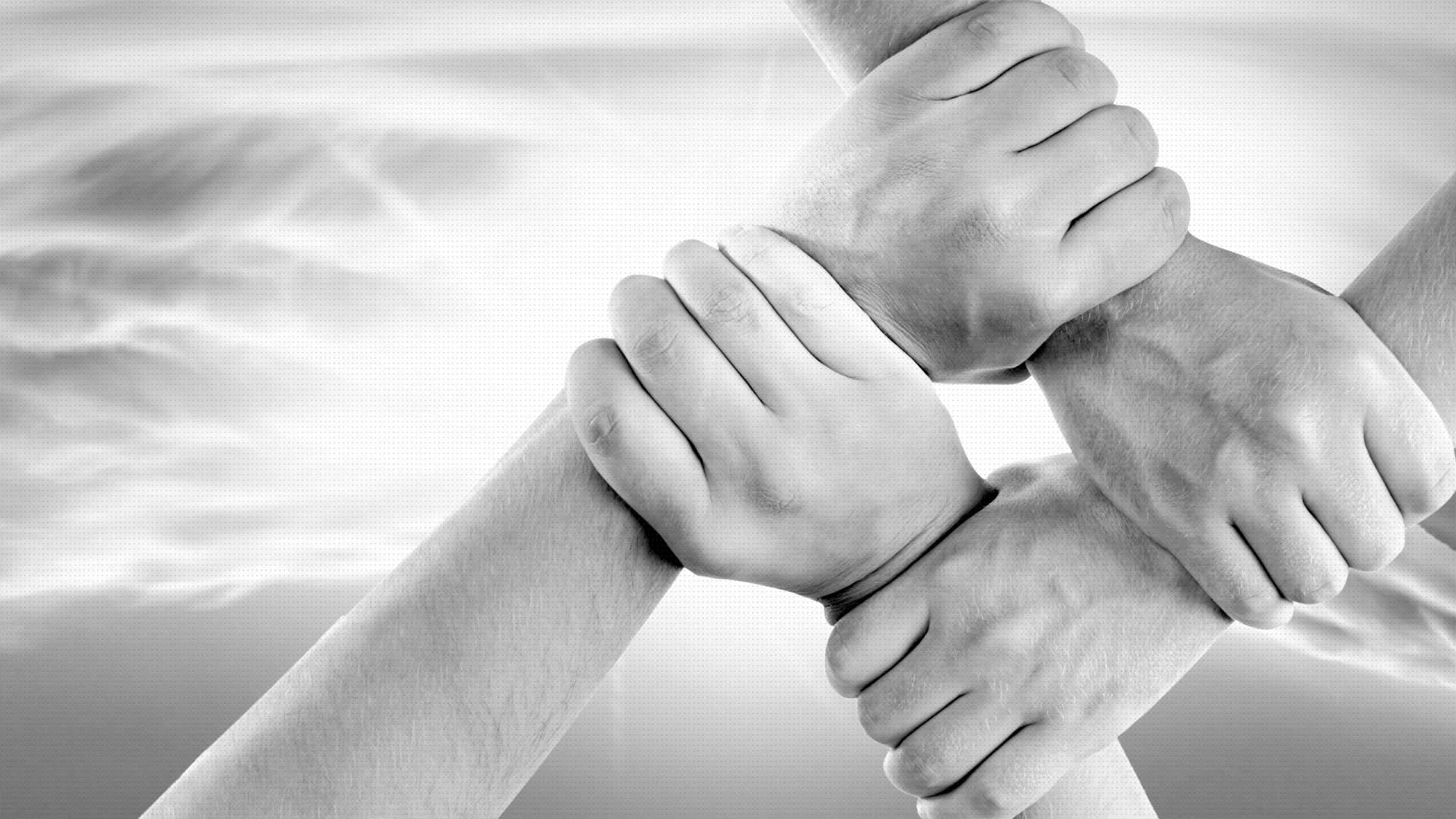 hands 桌布 壁紙 — 四隻手在柔和模糊的背景中緊緊握成一個圓圈。
