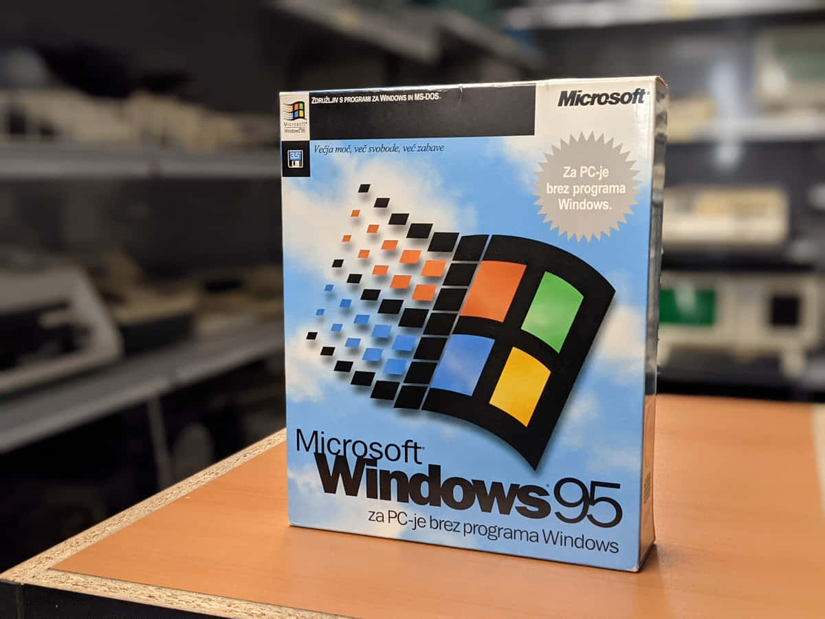 回憶 Windows 95 的年代 壁紙 — 一個復古的Microsoft Windows 95軟件盒直立於木質表面上，背景是模糊的科技工作坊。