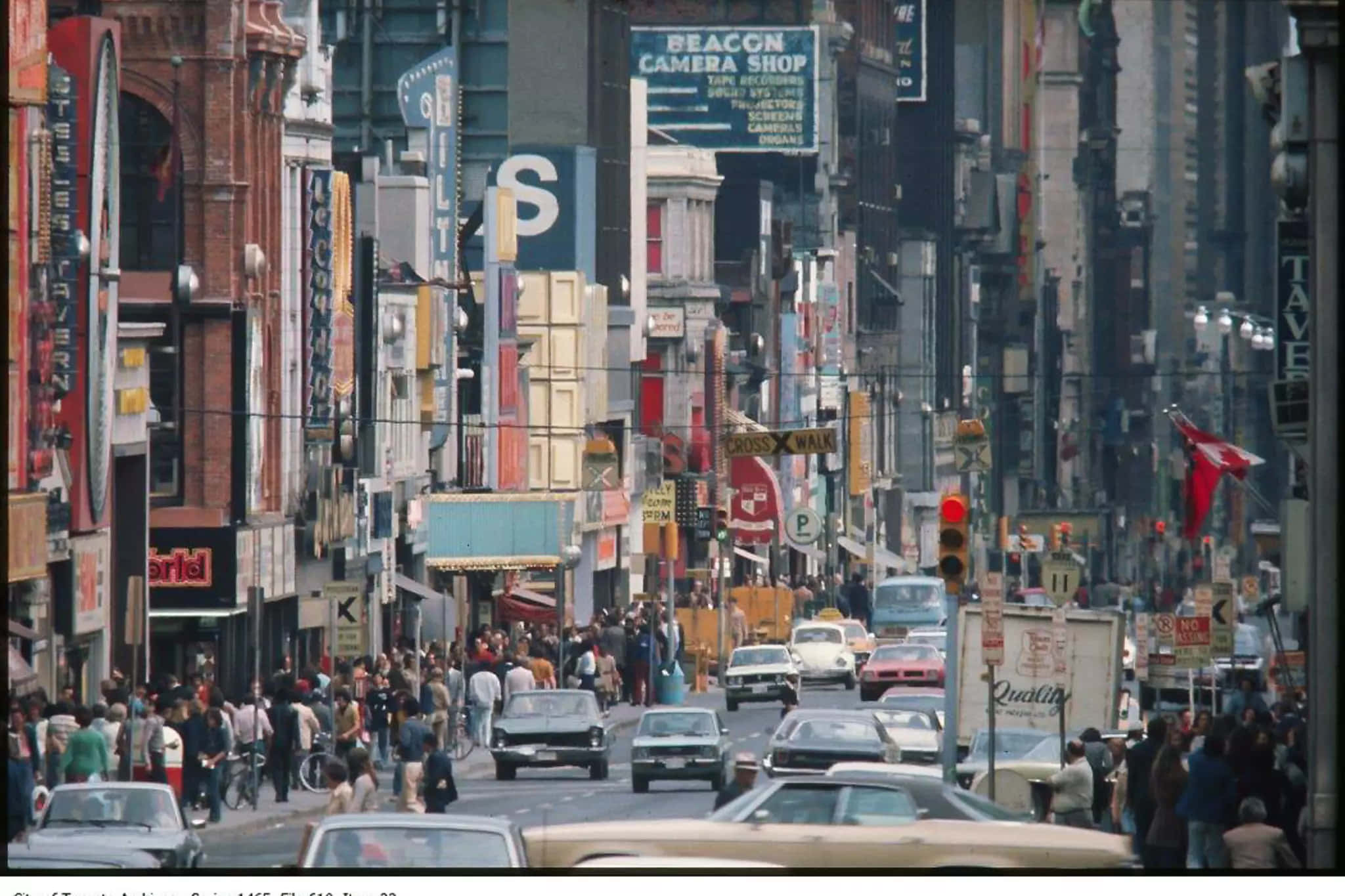 回憶1980年代——我們永遠不會忘記的十年 壁紙 — 一條繁華的1960年代城市街道，擠滿行人、老爺車和裝飾著色彩繽紛招牌和廣告的高聳建築物。