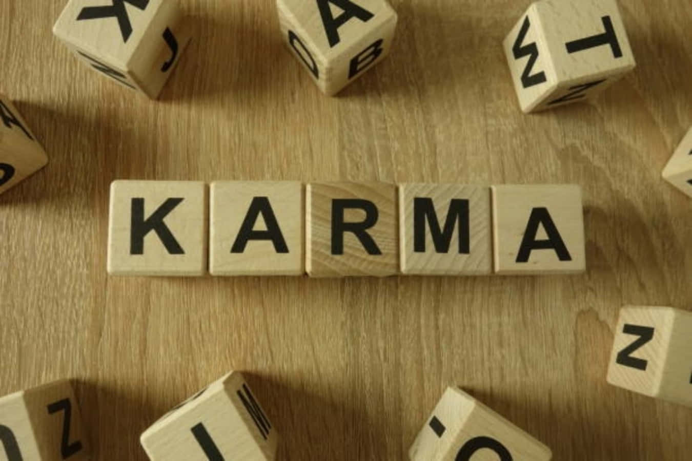 木製積木在木桌上拼出 karma，散落著字母方塊。