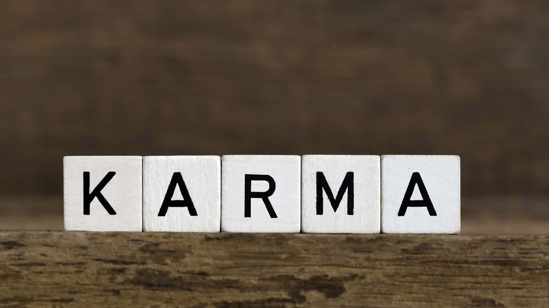 在質樸的木質表面上拼寫出 karma 的白色木塊。