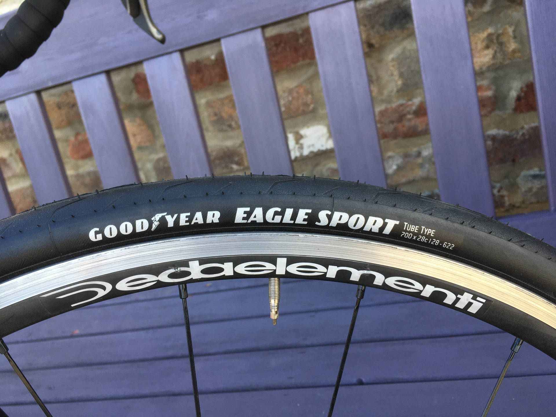 特寫鏡頭：紫色長椅上的 Goodyear Eagle Sport 單車輪胎。