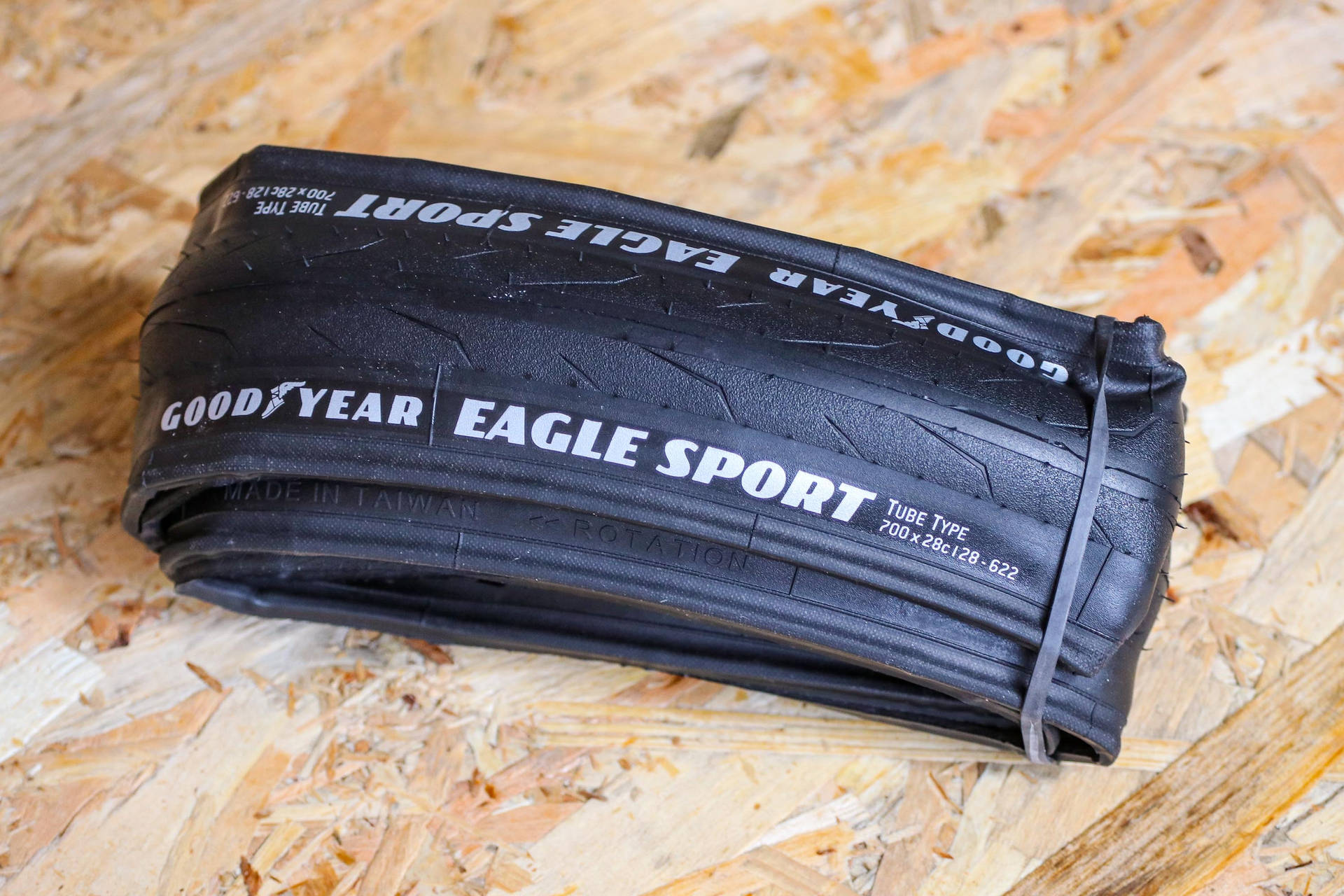 一條用橡筋捆綁的黑色Goodyear Eagle Sport單車輪胎在木頭上。