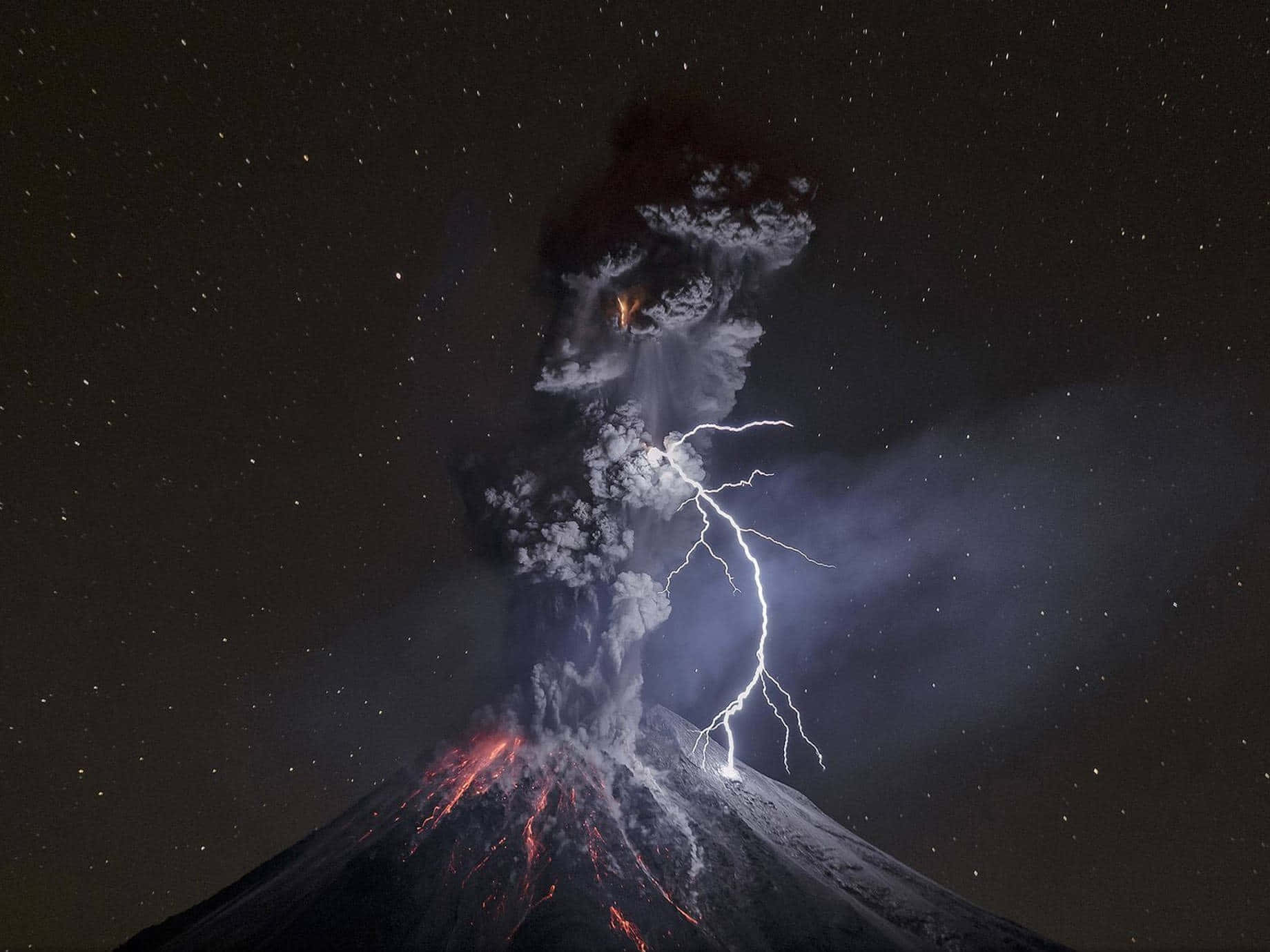 夜晚火山爆發，閃電和發光熔岩，星空下。
