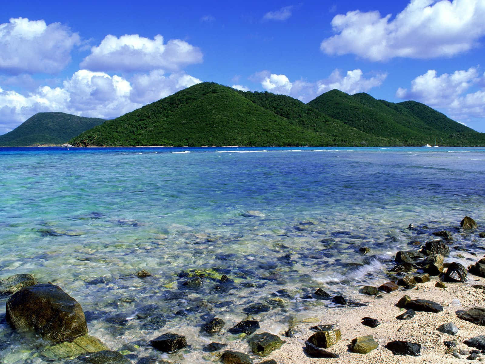 熱帶海灘，清澈海水和綠色山丘，藍天白雲