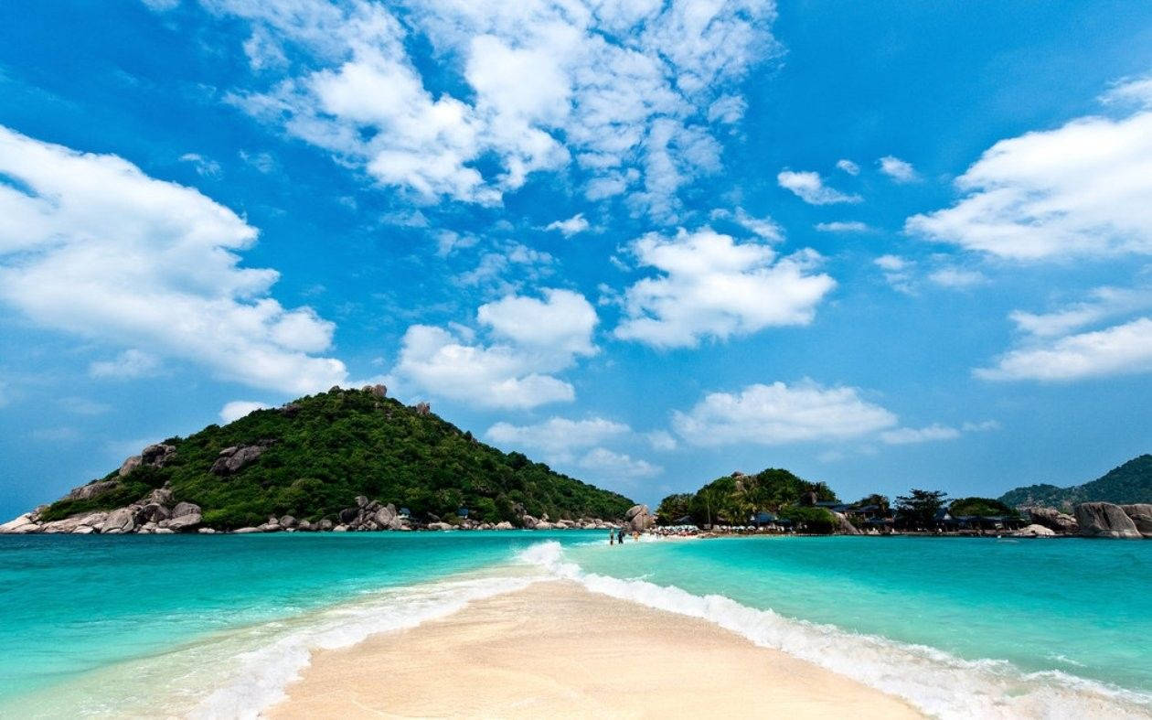熱帶海灘，碧綠海水和綠色島嶼，藍天白雲