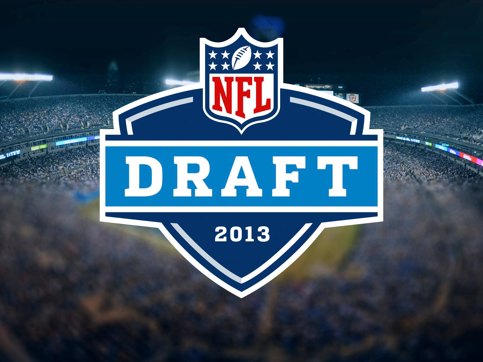 國家美式足球聯盟酷炫標誌 壁紙 — NFL Draft 2013 標誌突出顯示在一個模糊的夜間體育場上，場內擠滿了歡呼的球迷。
