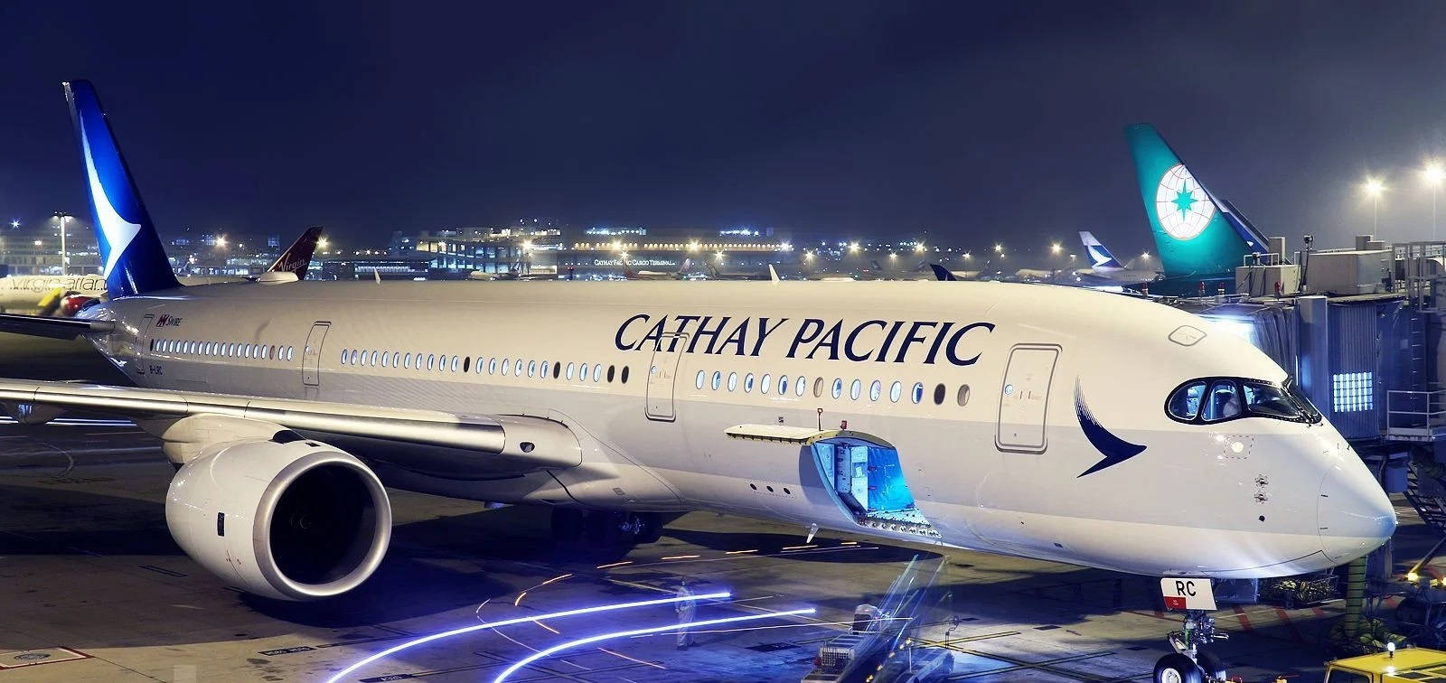 國泰航空飛機夜間停泊，帶有登機梯和跑道燈光。