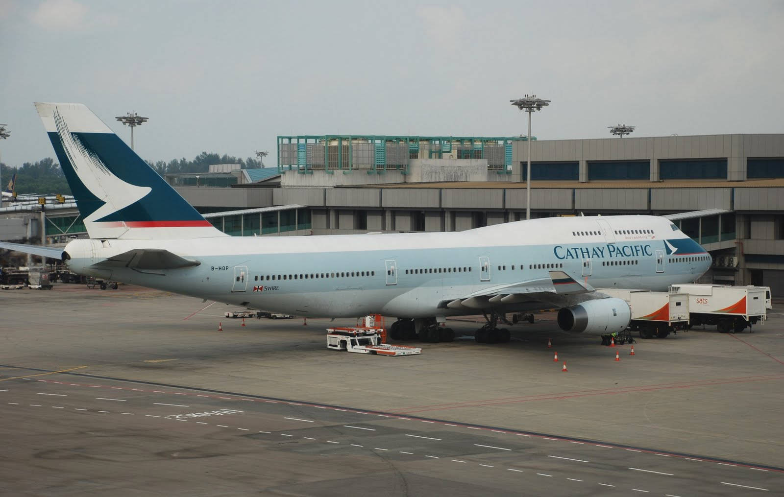 國泰航空飛機停泊在機場閘口，有地勤服務車輛。